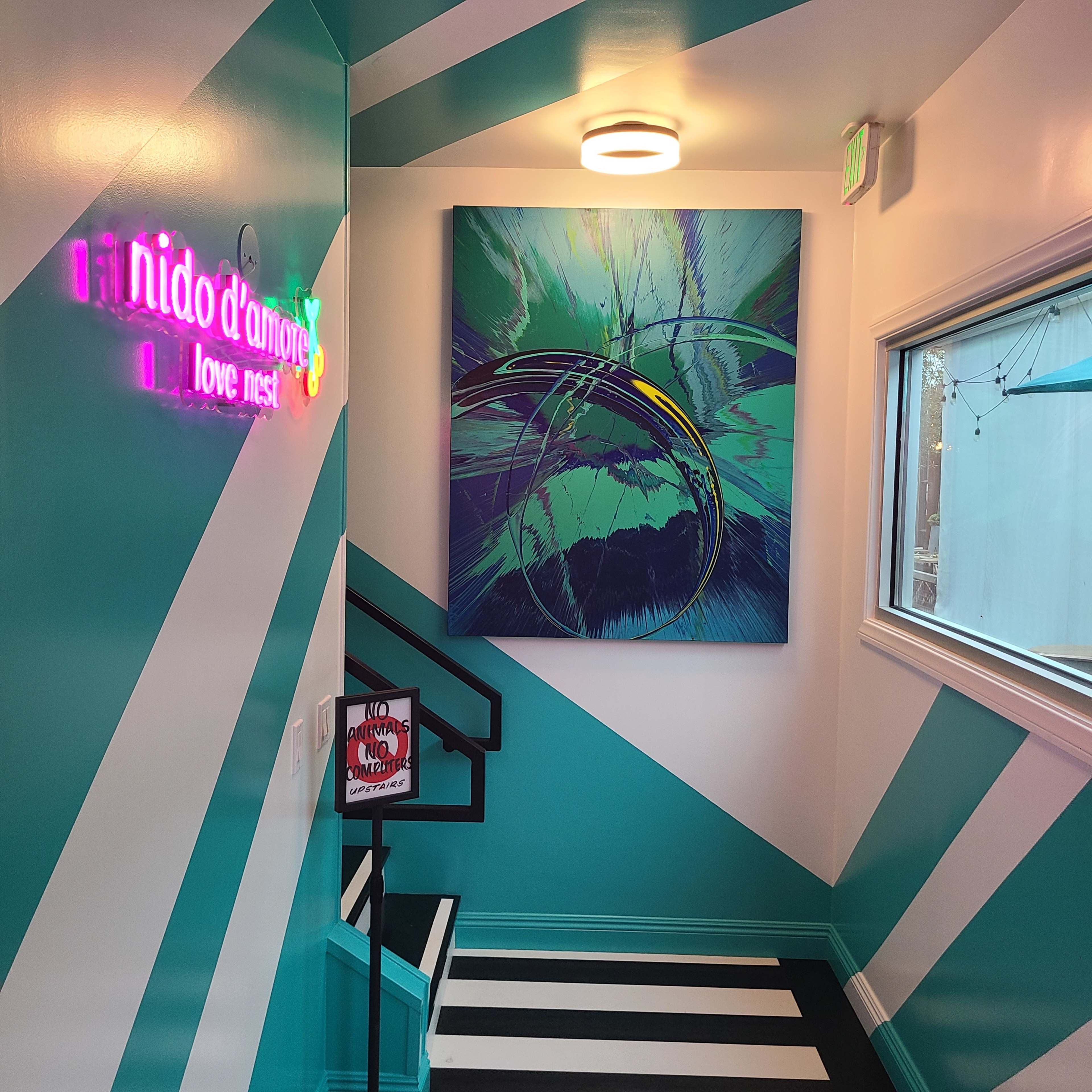 A brightly colored staircase features teal and white striped walls, with a large abstract painting and neon signs.