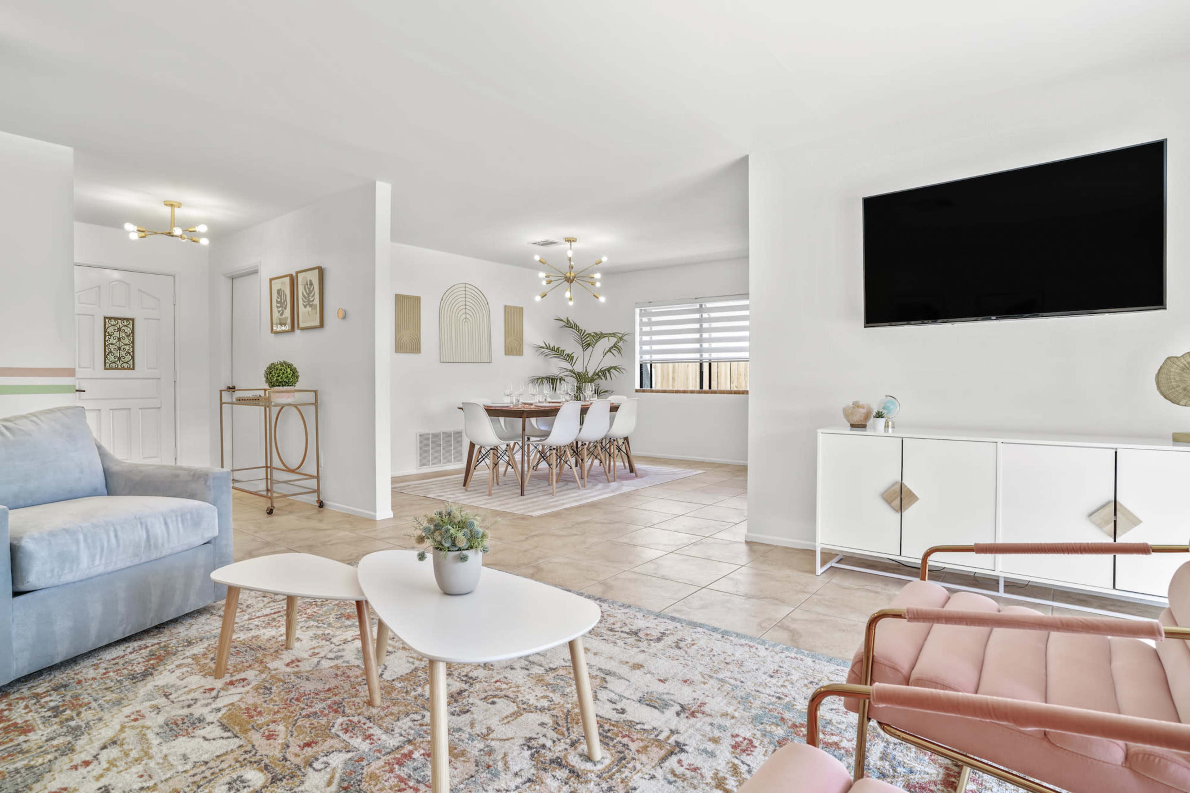 A modern living area with a light-colored sofa, a coffee table, and a dining space with a large table and chairs, all arranged in a bright, open layout.