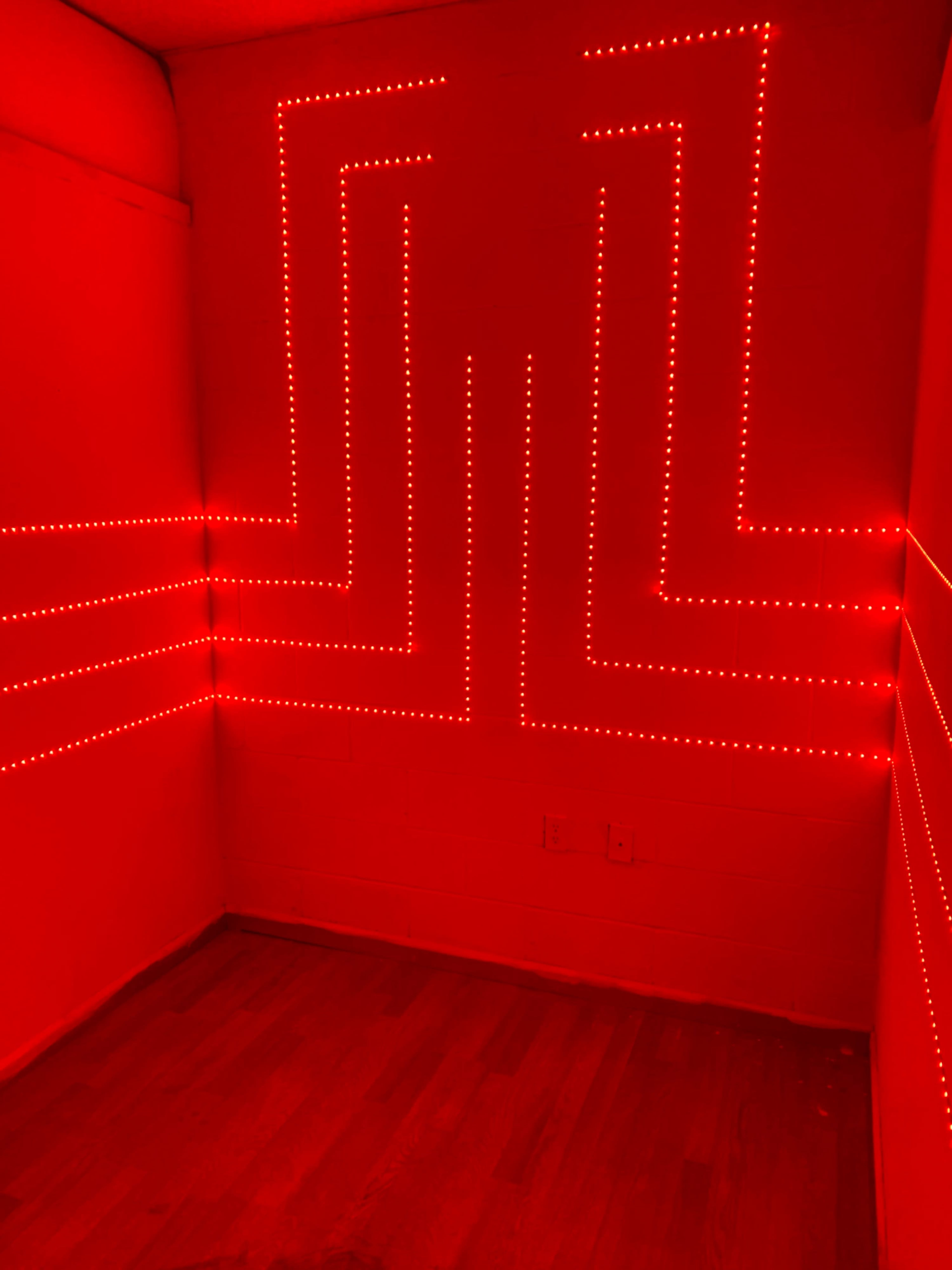 A room is illuminated with red LED lights arranged in a circuit-like pattern on the walls.