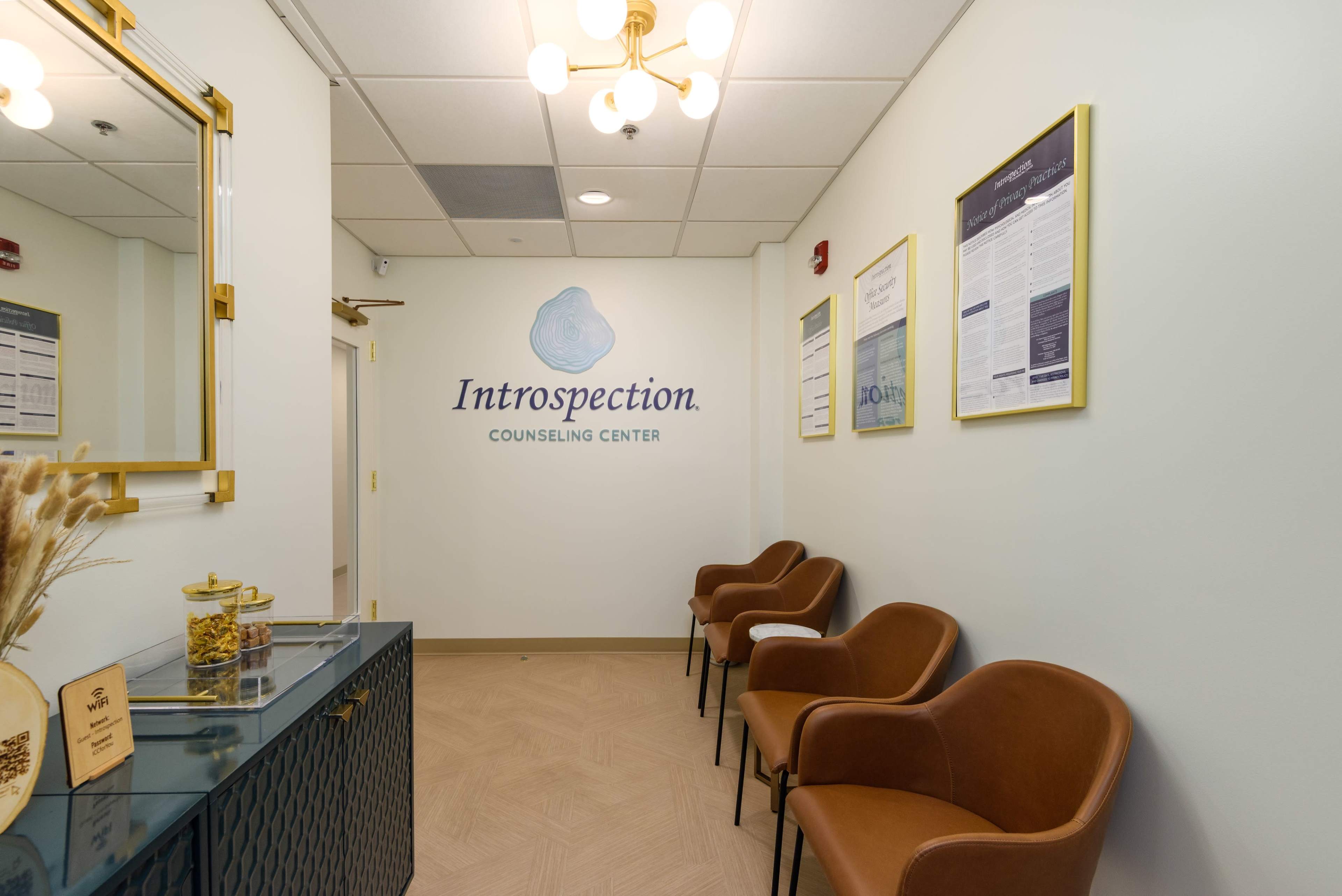 The image shows a modern waiting area in a counseling center, featuring brown chairs, a decorative cabinet, and informational posters on the walls.