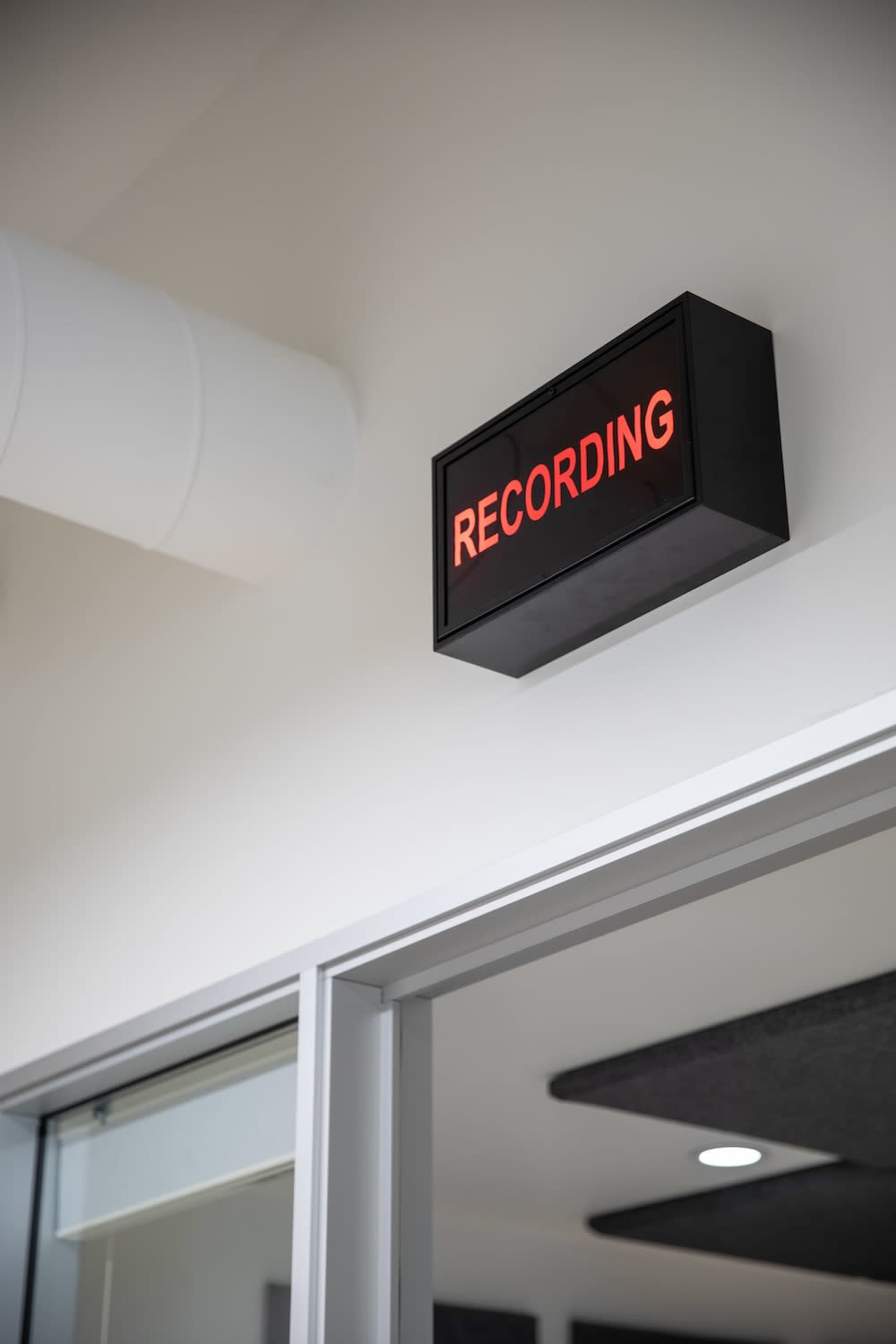 A sign that reads "RECORDING" is mounted on the wall above an open doorway.