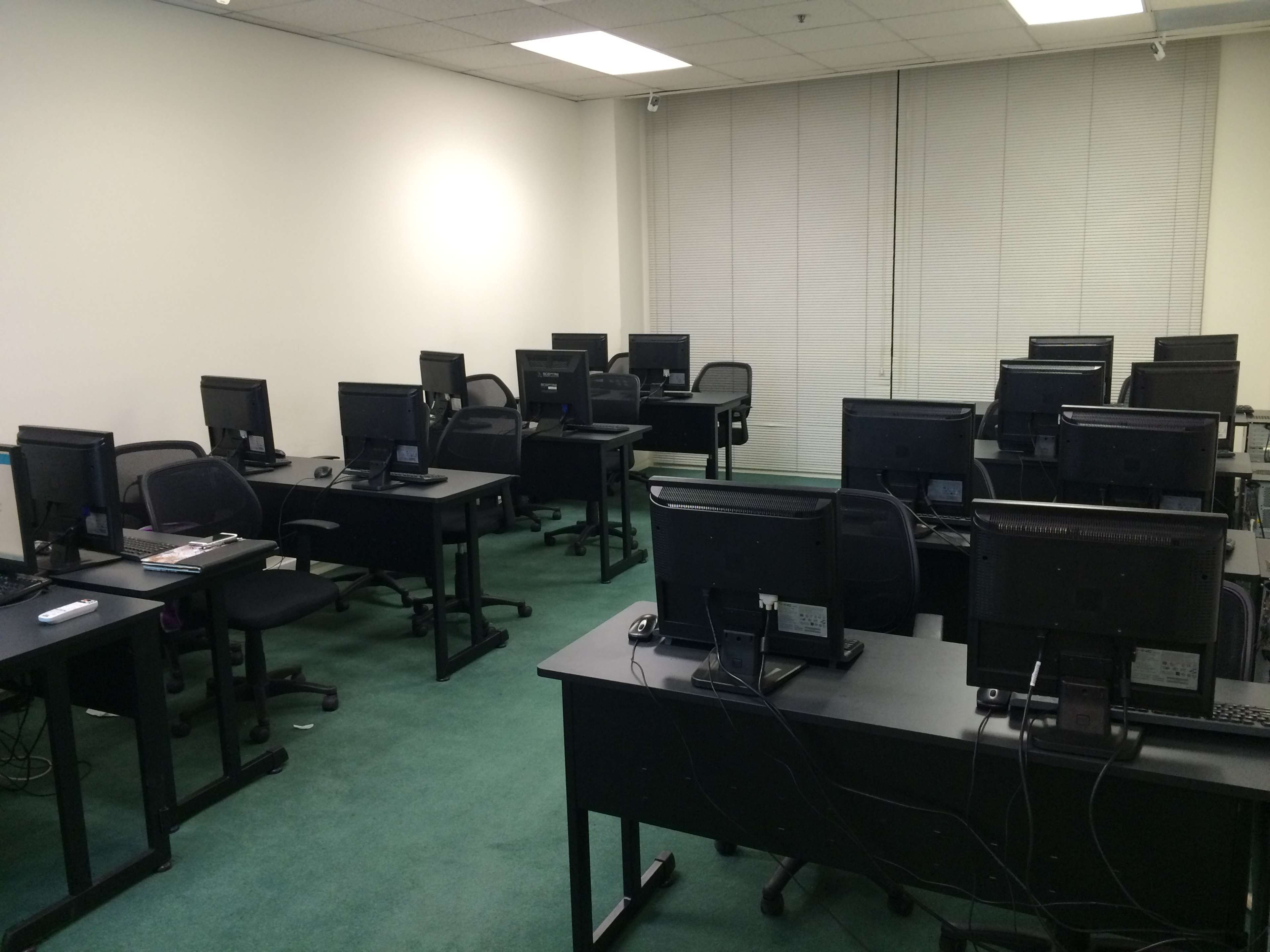 A row of desks with computers in a sparsely furnished office space.