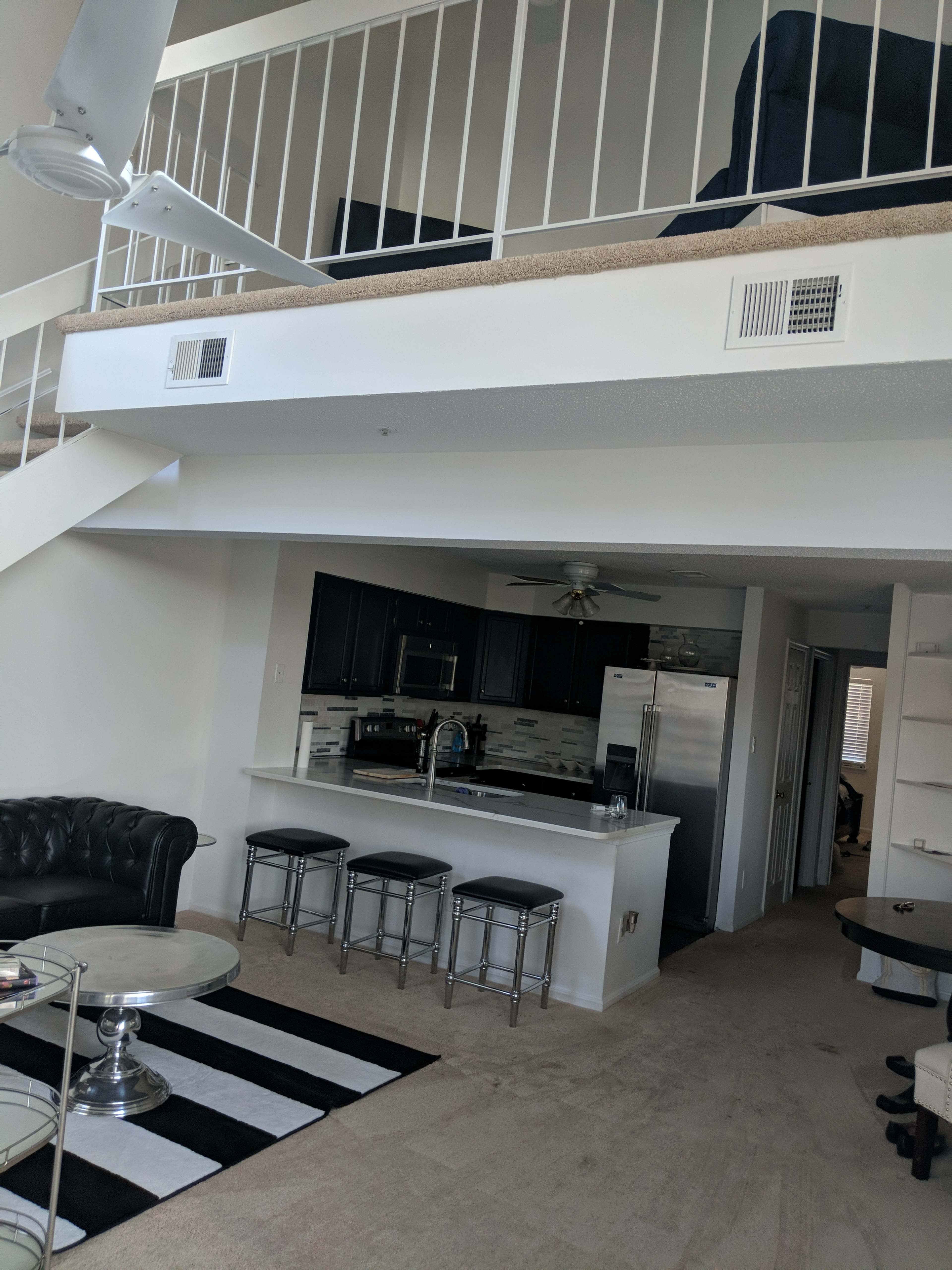 A modern open-concept living space with a kitchen, dining area, and a staircase leading to a loft.