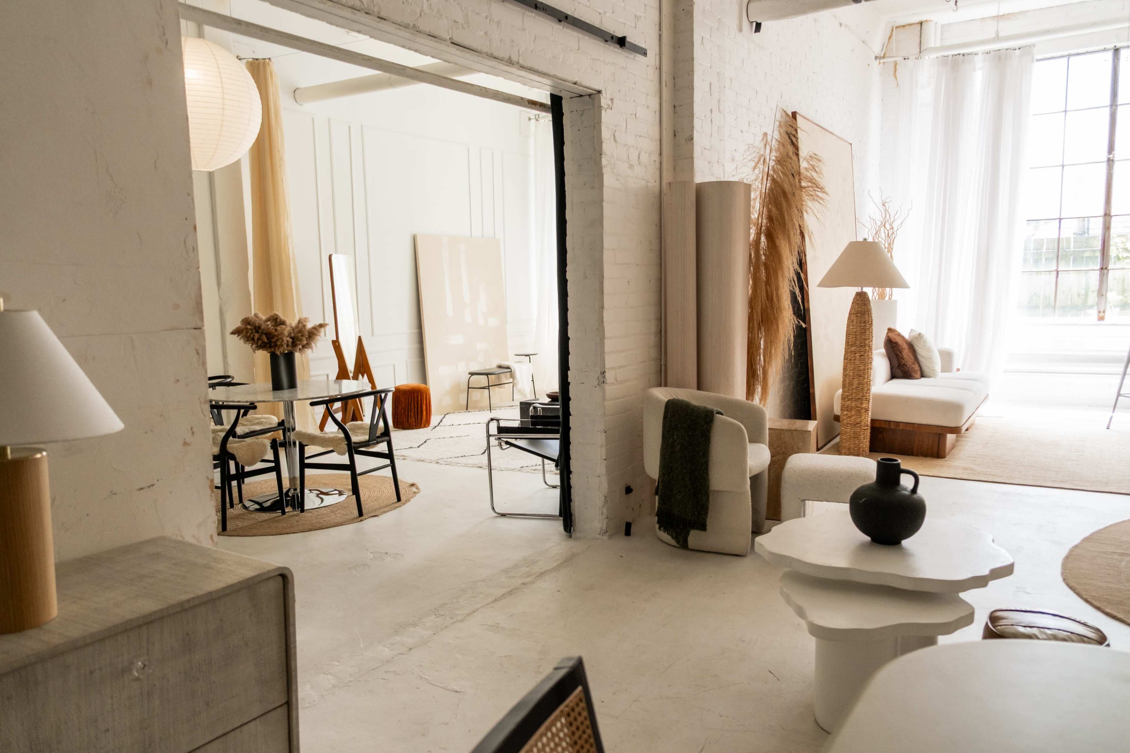 The image shows a stylish, modern interior space featuring sleek furniture, decorative elements, and large windows providing natural light.