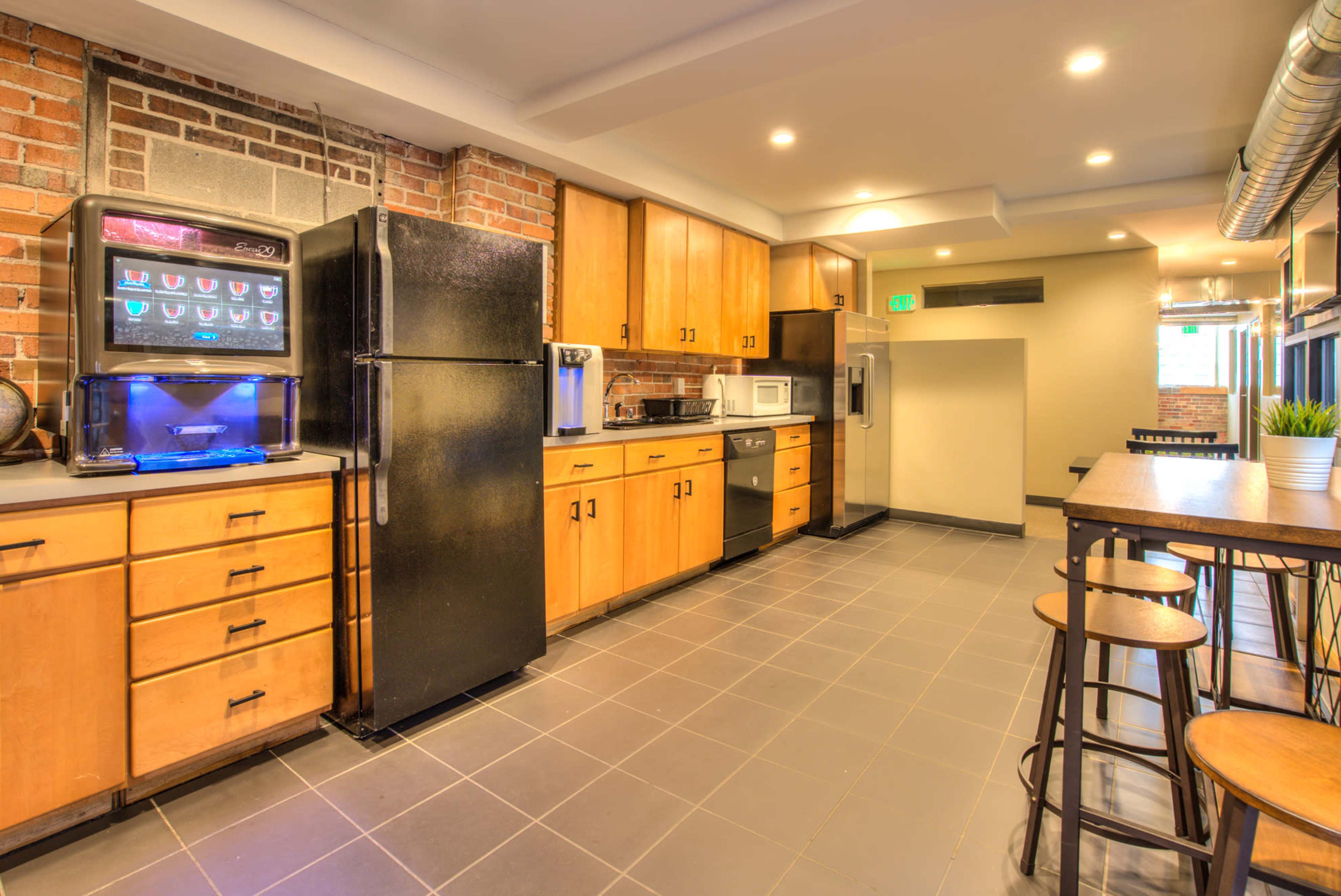 A modern kitchen with wooden cabinets, stainless steel appliances, and a dining area featuring bar stools.