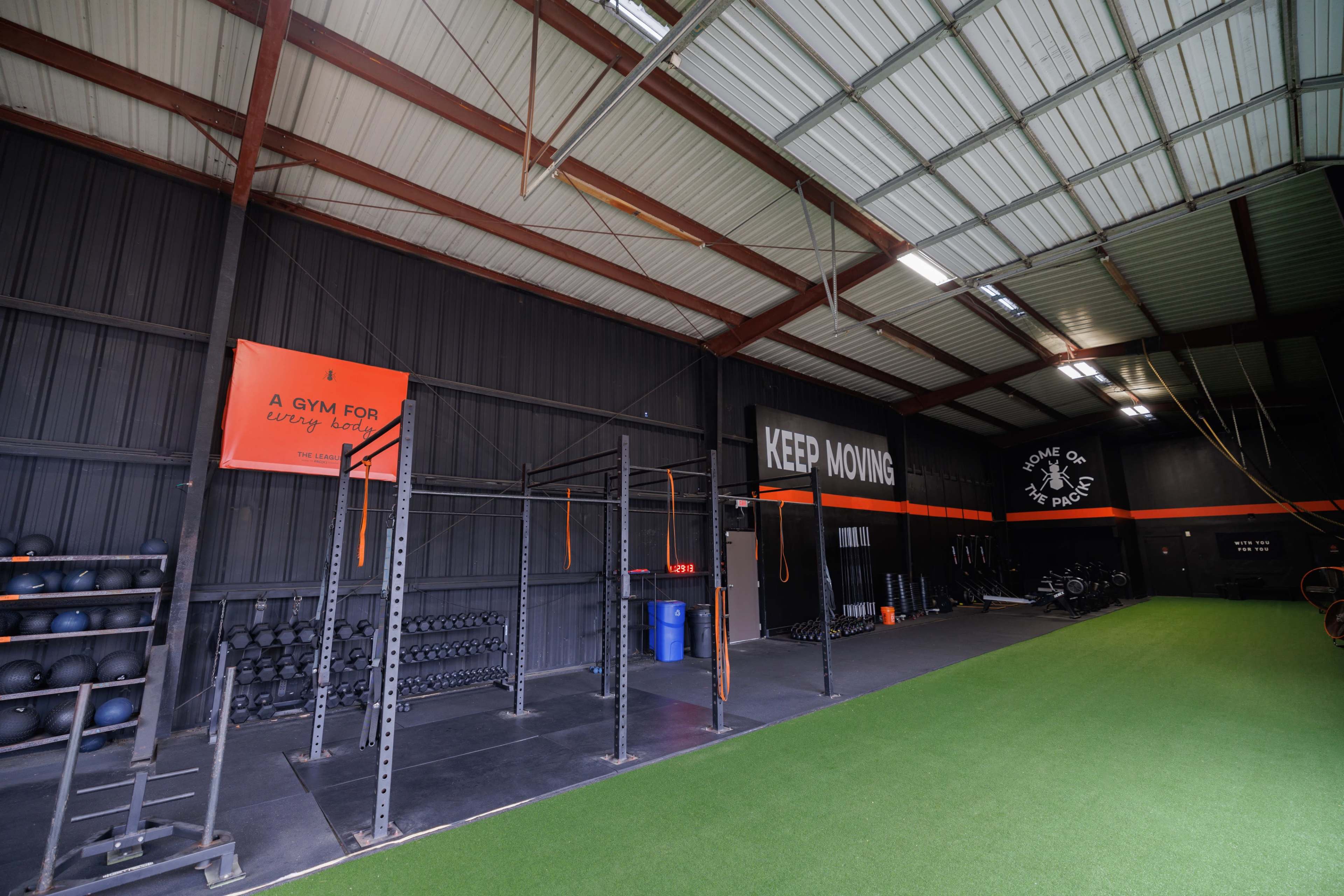 A spacious gym interior with weightlifting equipment, exercise mats, and motivational signage on the walls.