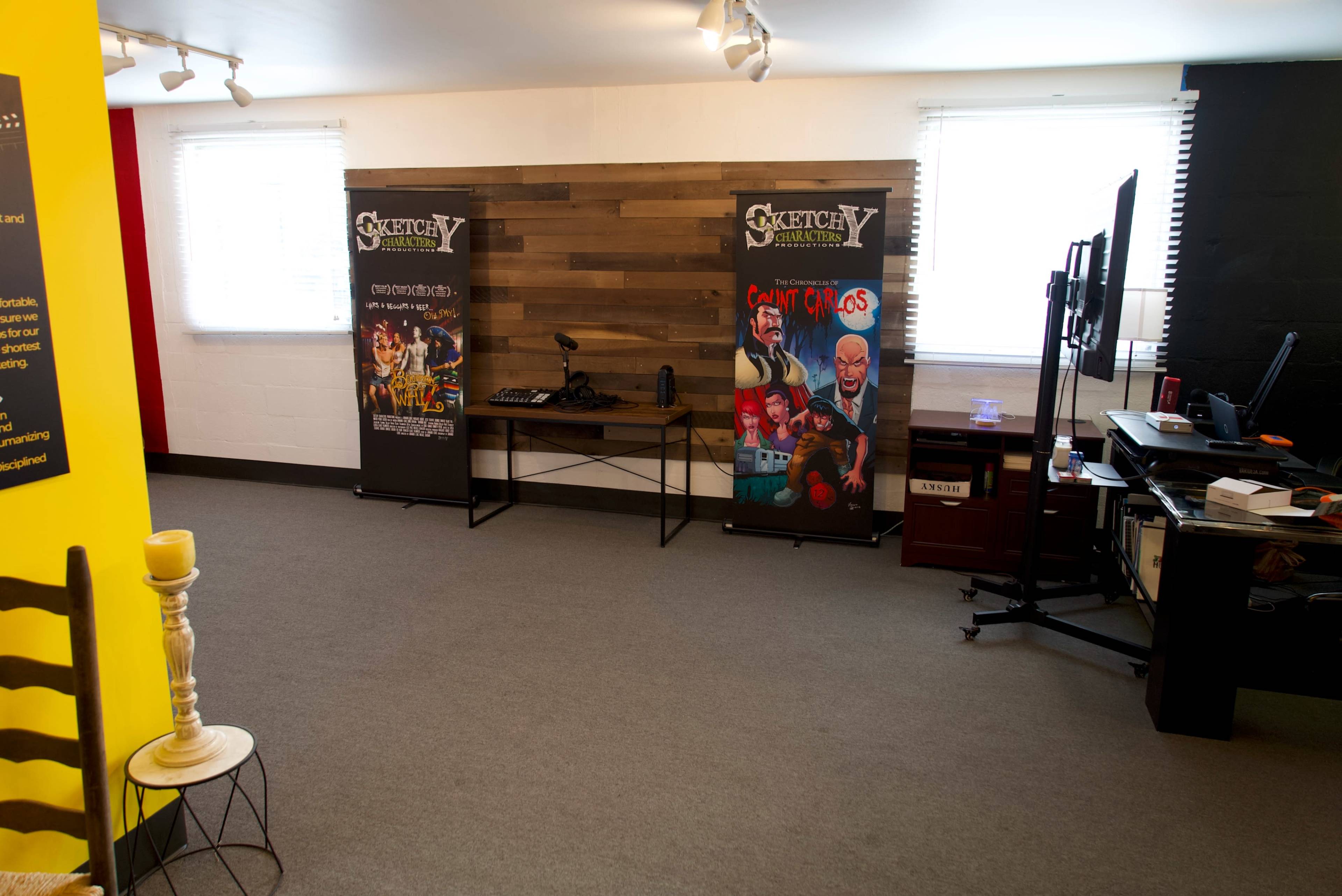 A modern workspace featuring two promotional banners, a desk with a computer setup, and a carpeted floor in a well-lit room.