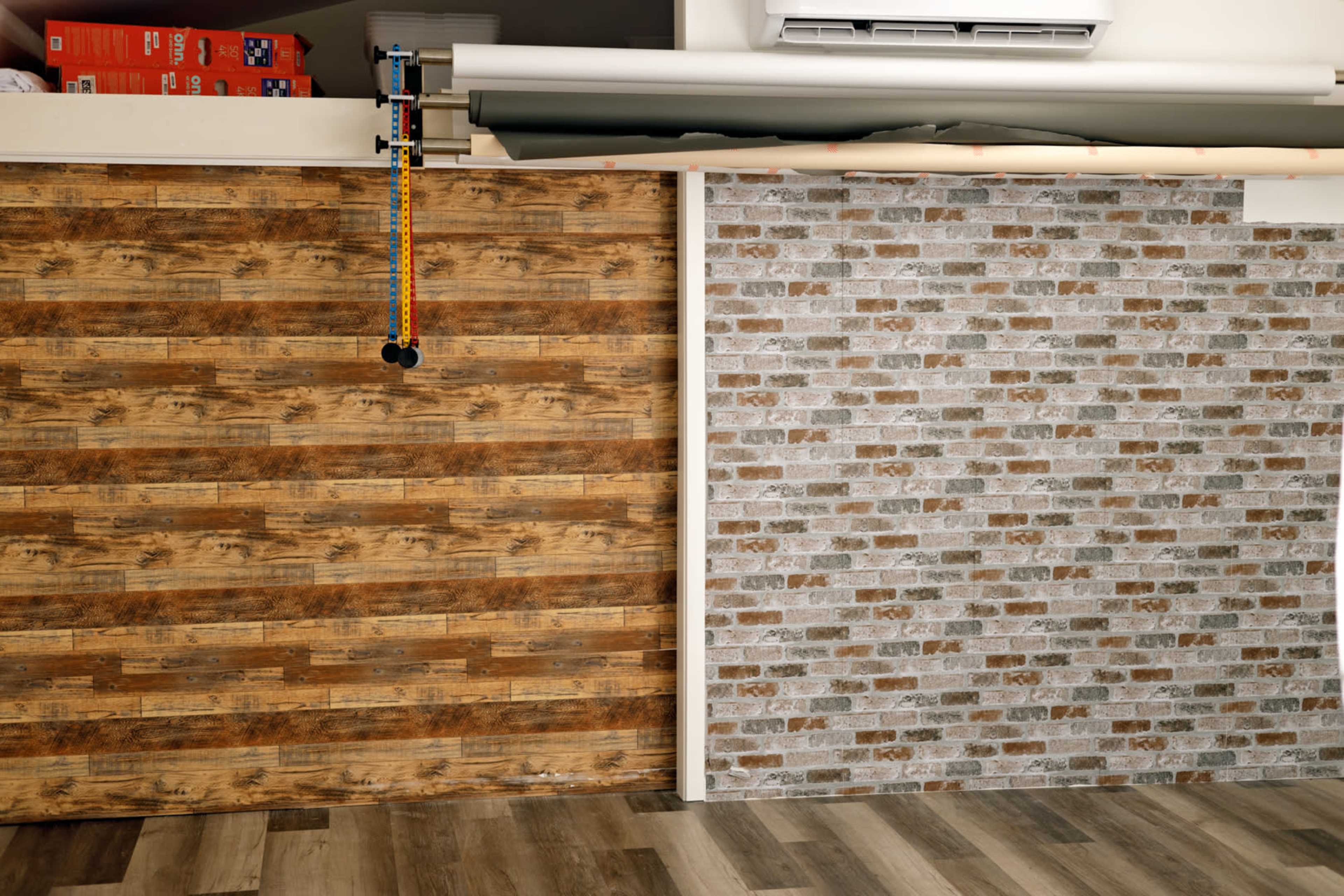 A split wall design featuring a wooden panel texture on one side and a gray brick pattern on the other, with a roll of material hanging above.