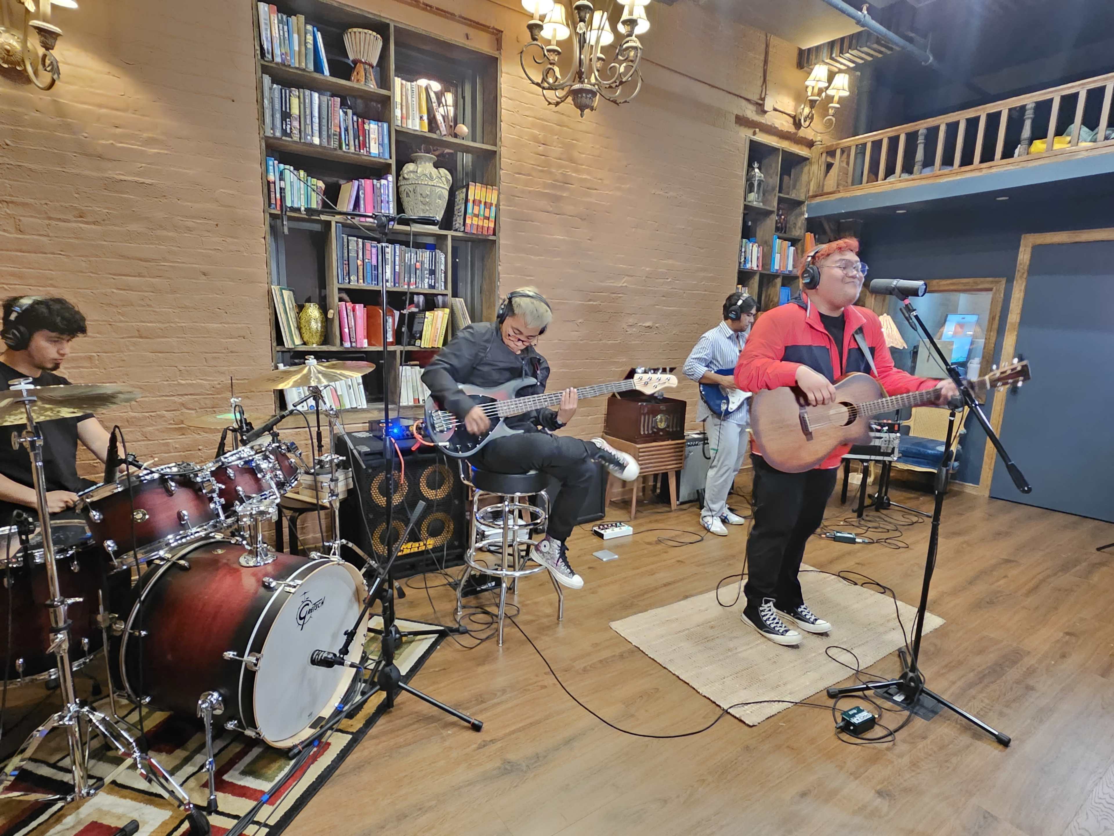A band performs live music in a cozy venue surrounded by bookshelves.