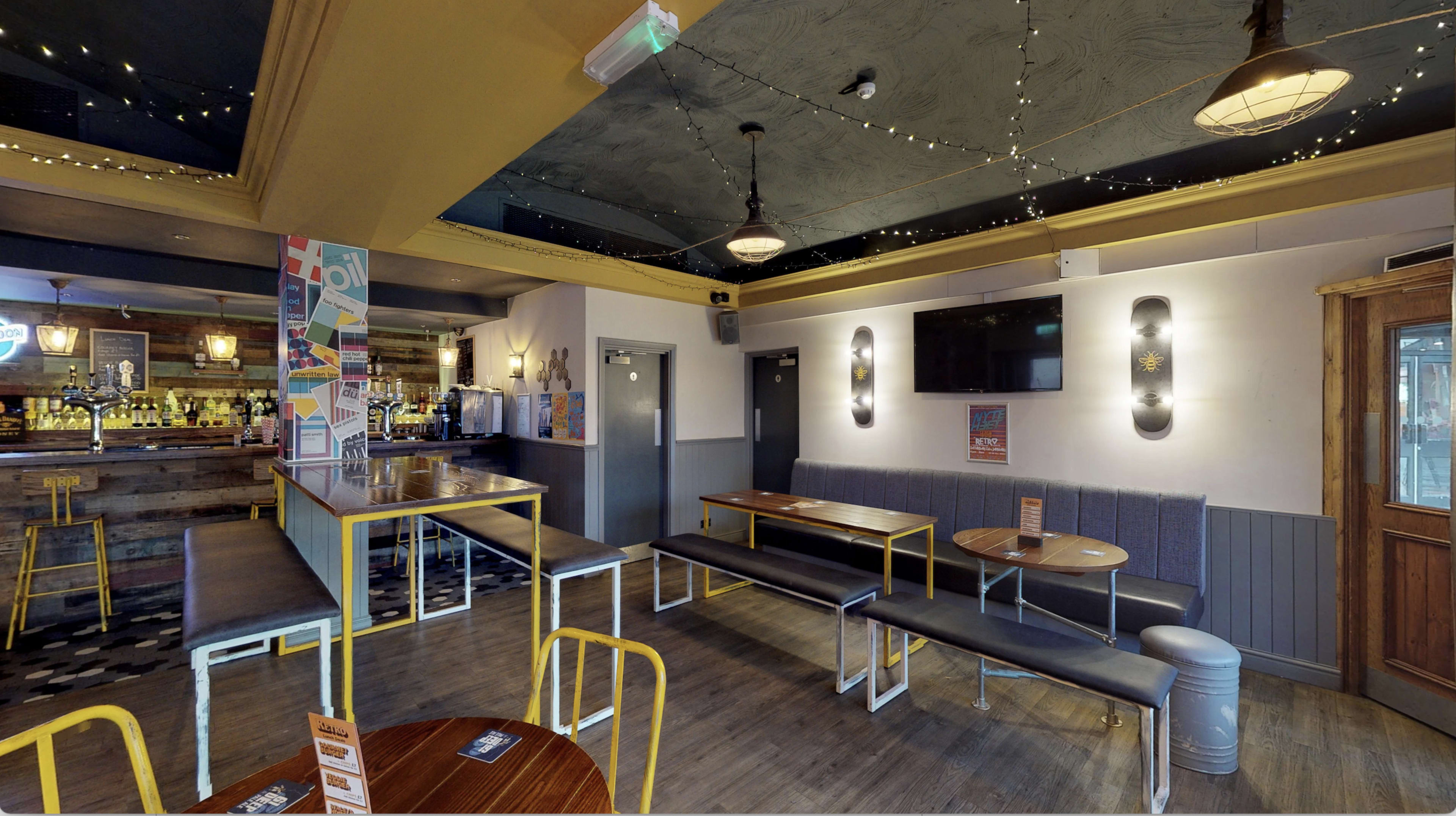 The interior of a bar with seating areas, a bar counter, and decorative lighting.