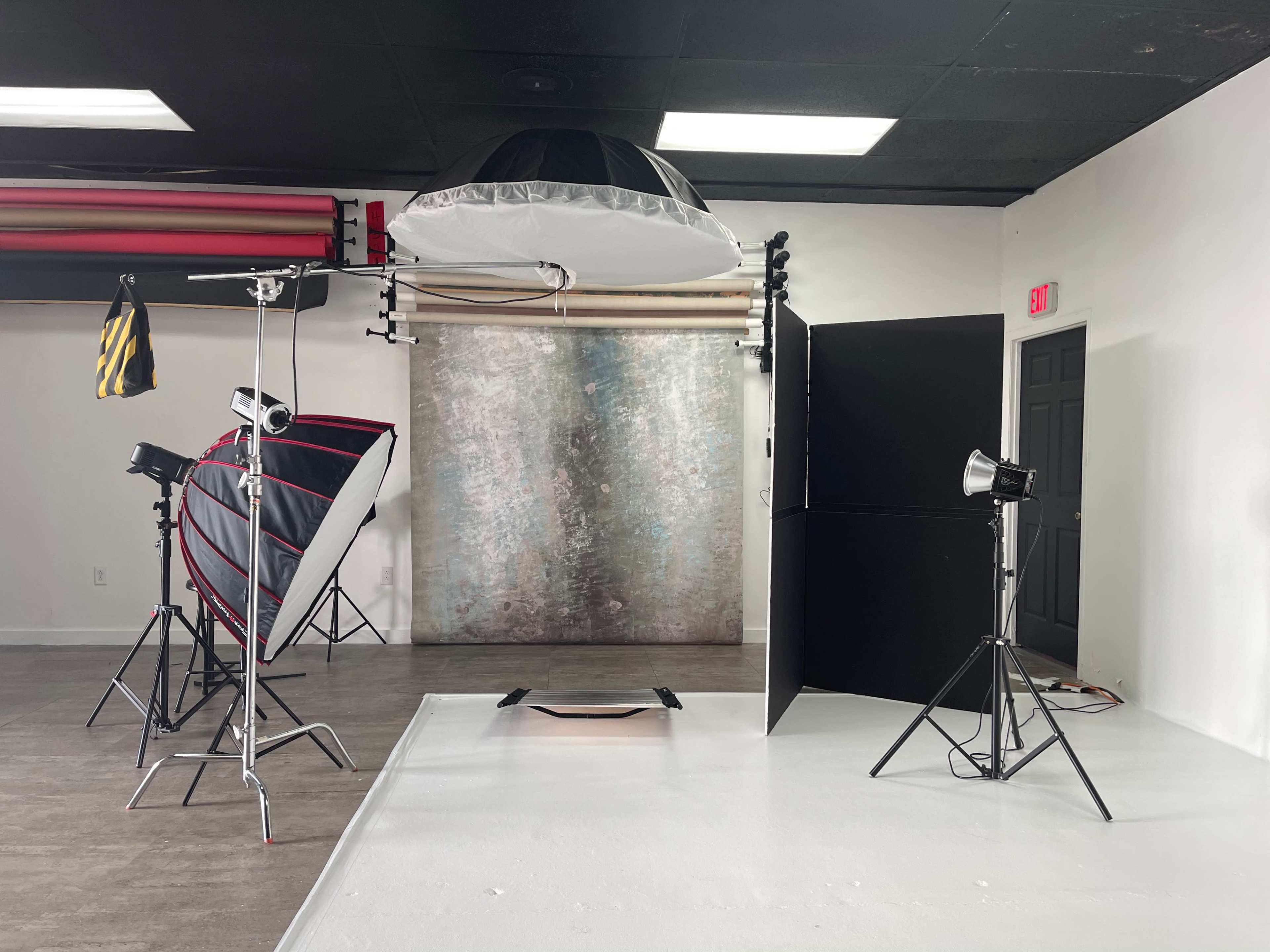 A photography studio setup featuring multiple light sources, backdrops, and a reflective umbrella.