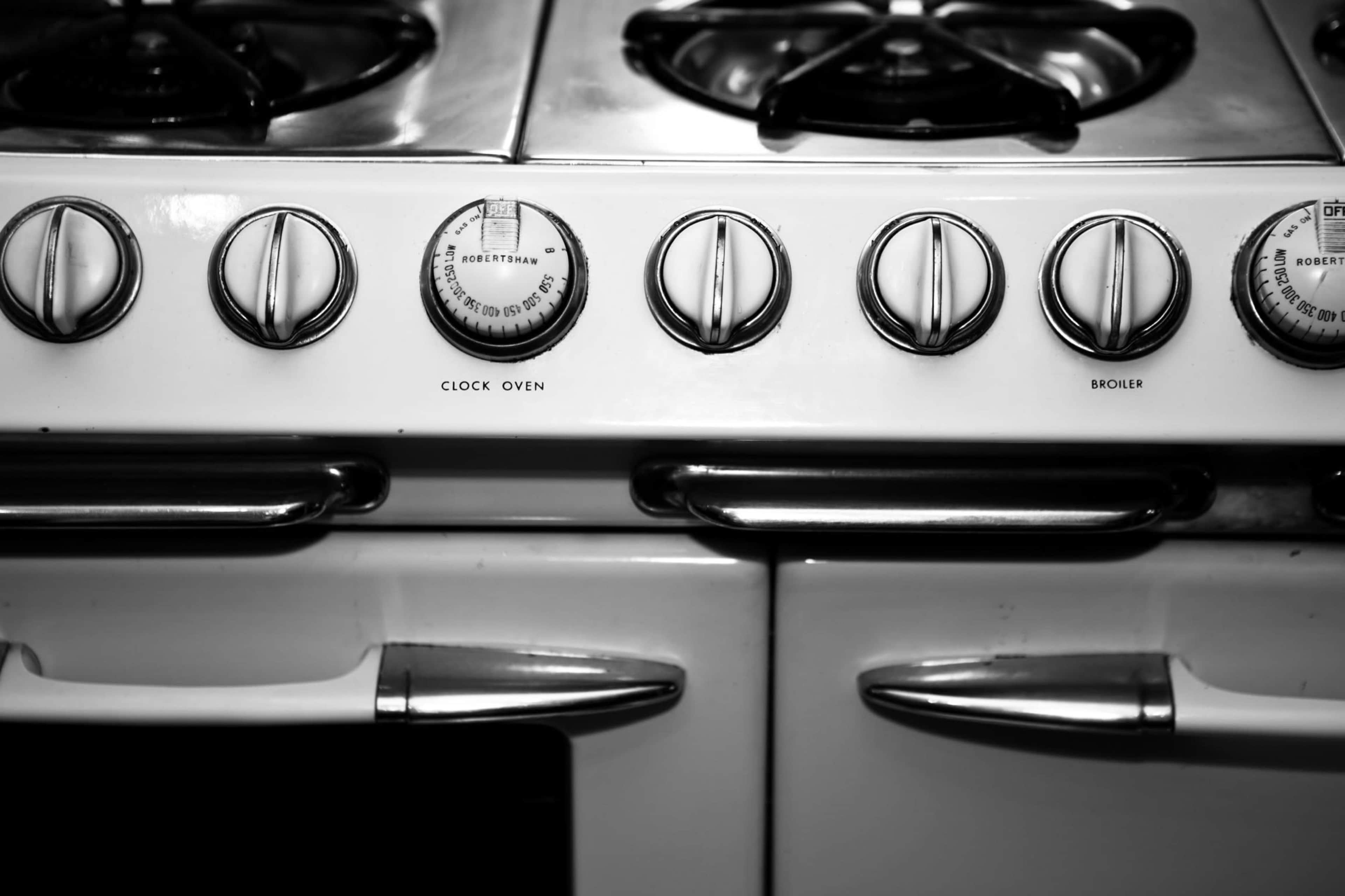 The image shows the control panel of a vintage gas stove with dials for the clock oven and broiler.