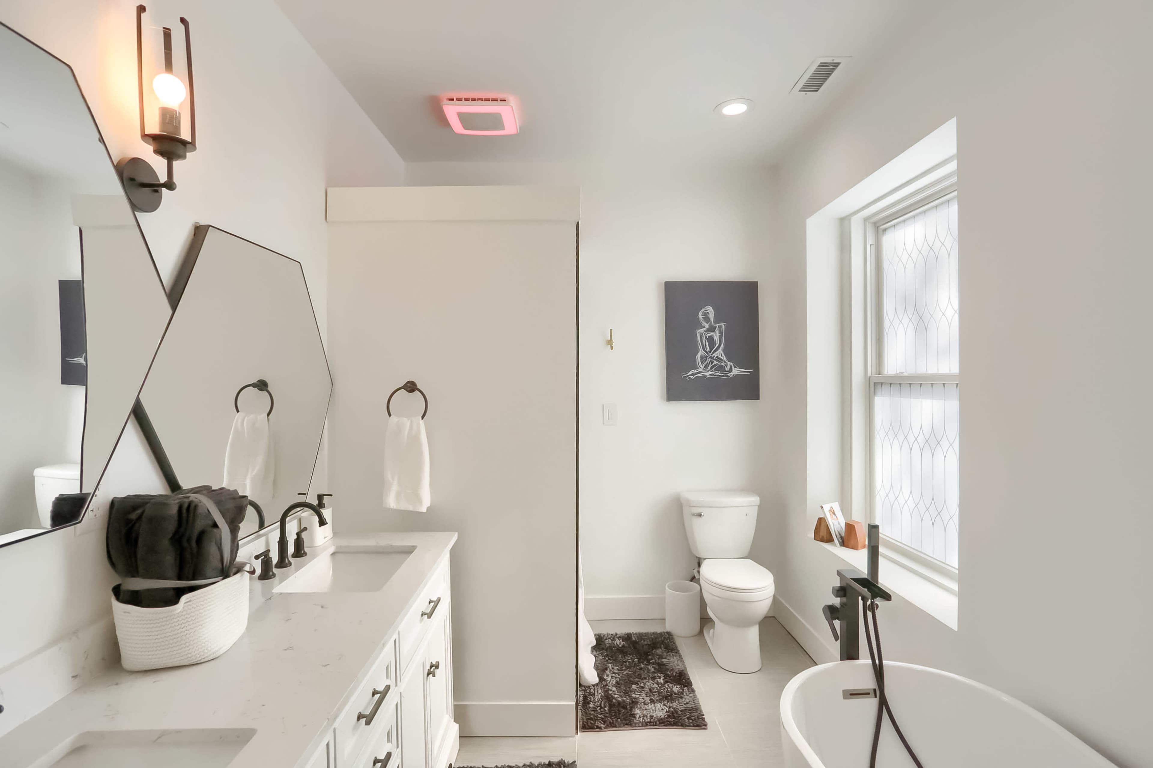 A modern bathroom with a double sink vanity, a freestanding bathtub, and a framed artwork on the wall.