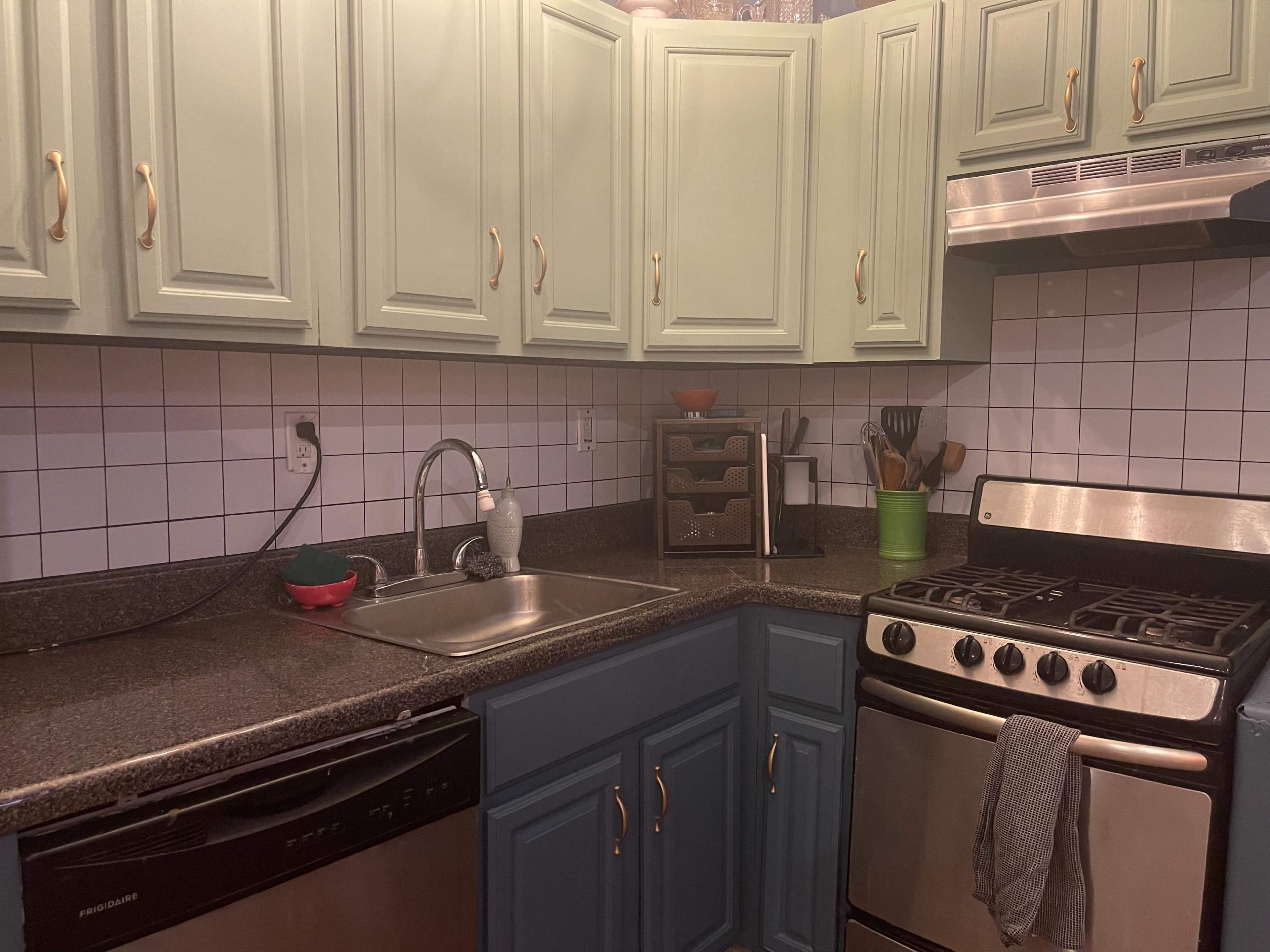 The image shows a kitchen with mint green cabinets, a stainless steel stove, and a dark countertop.