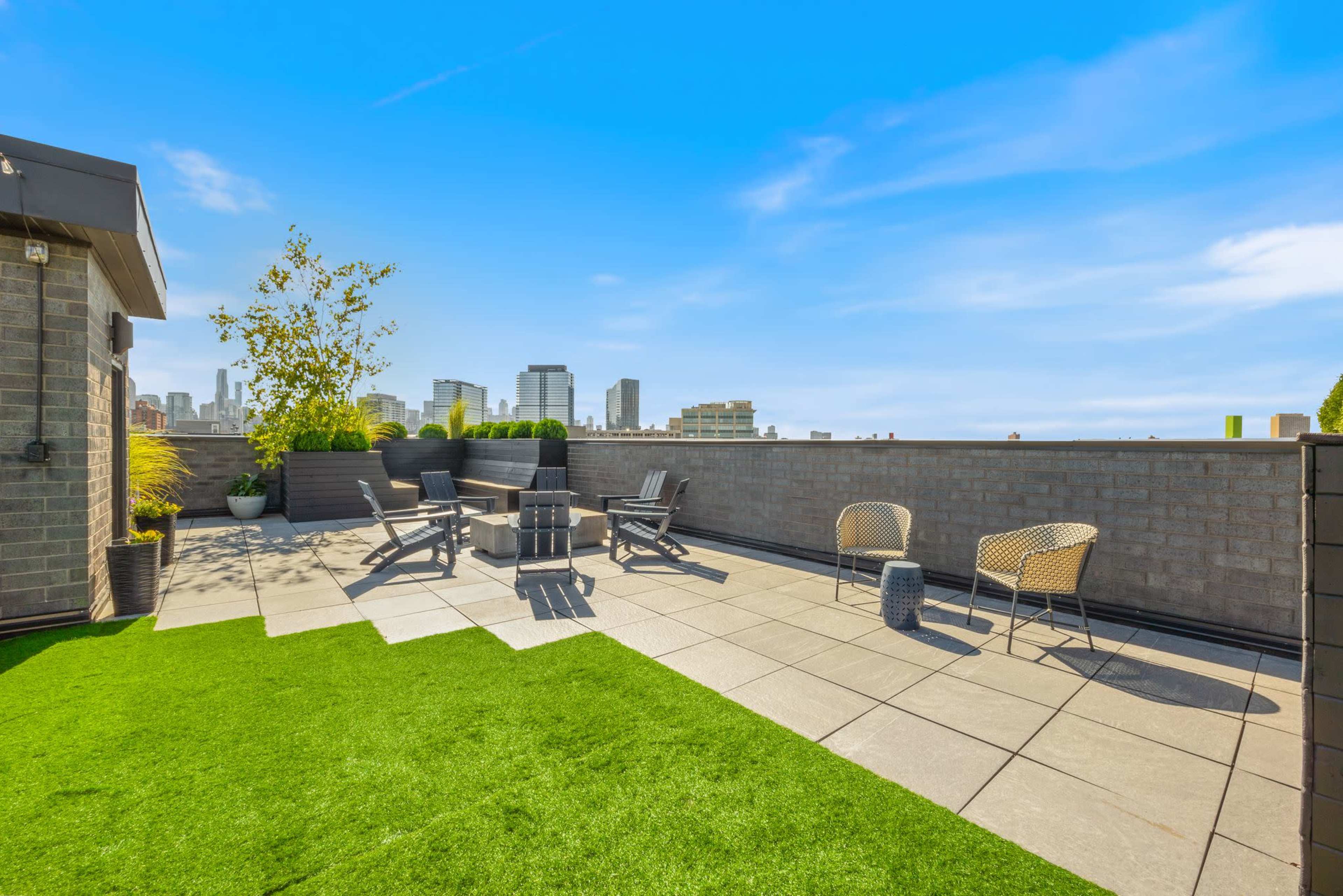 A rooftop terrace features a green turf area, seating arrangements, and a city skyline in the background.