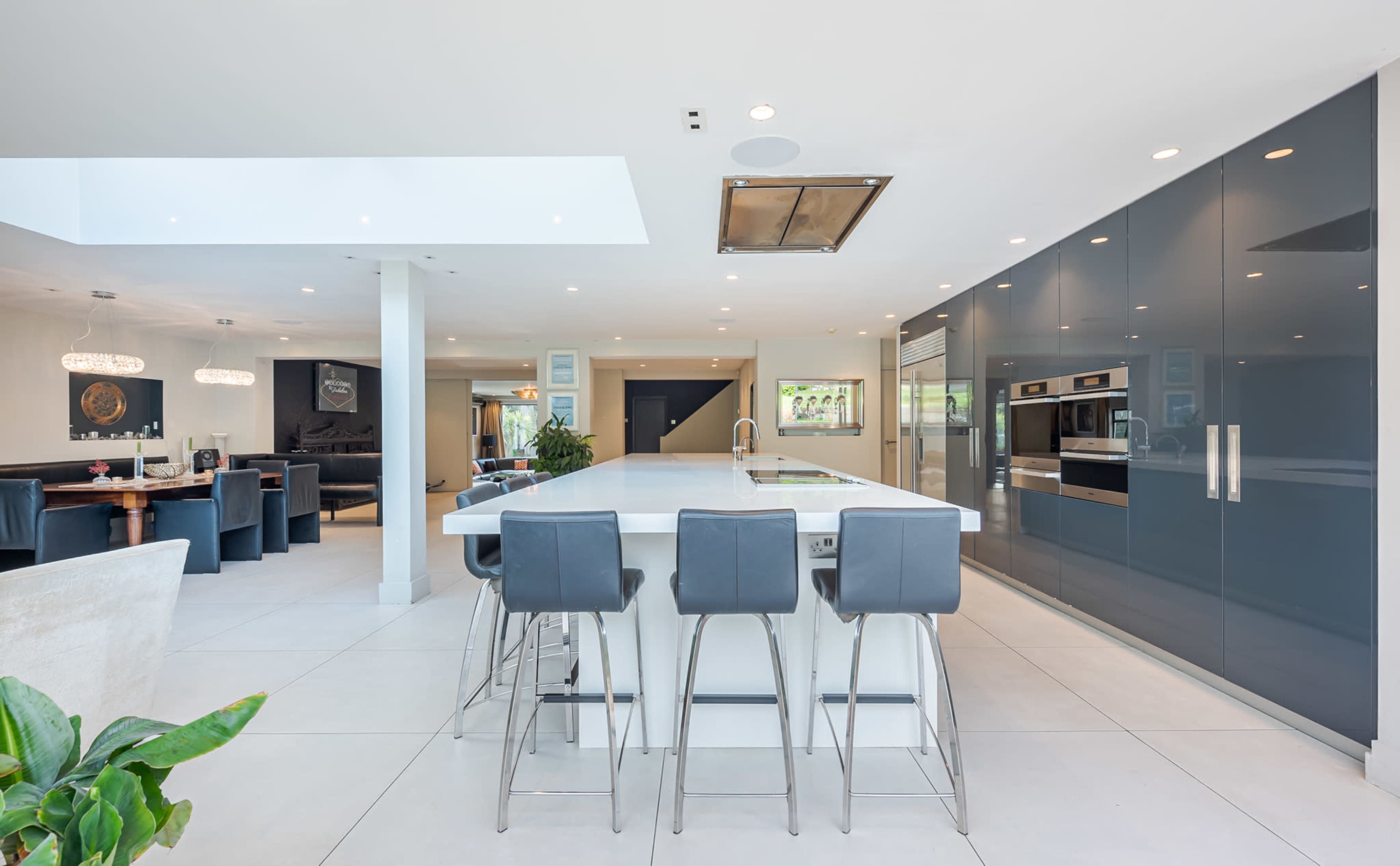 A modern kitchen with a large island, sleek cabinetry, and a spacious open layout connecting to a dining area.