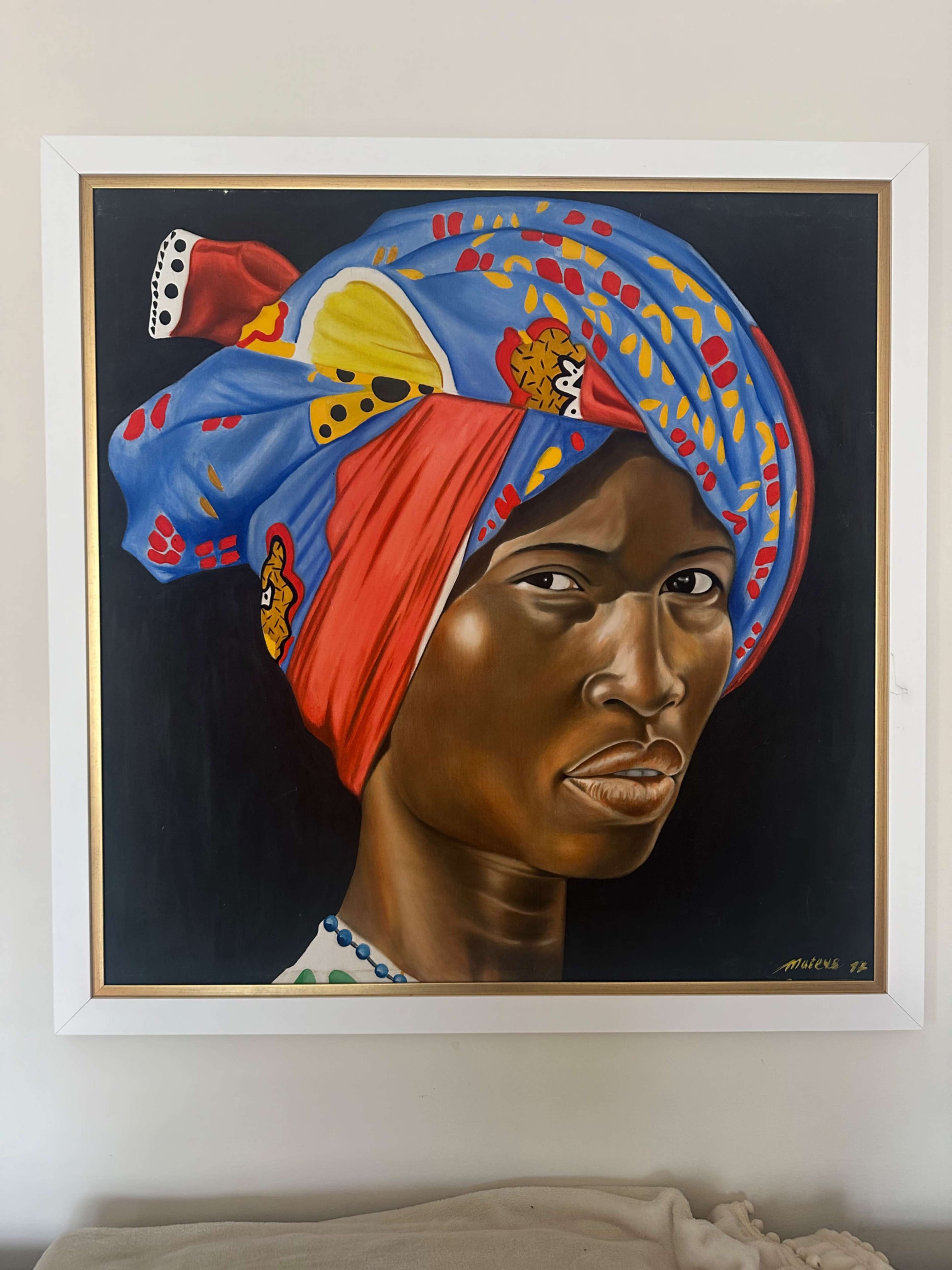The image depicts a portrait of a woman with a colorful head wrap, gazing directly at the viewer.