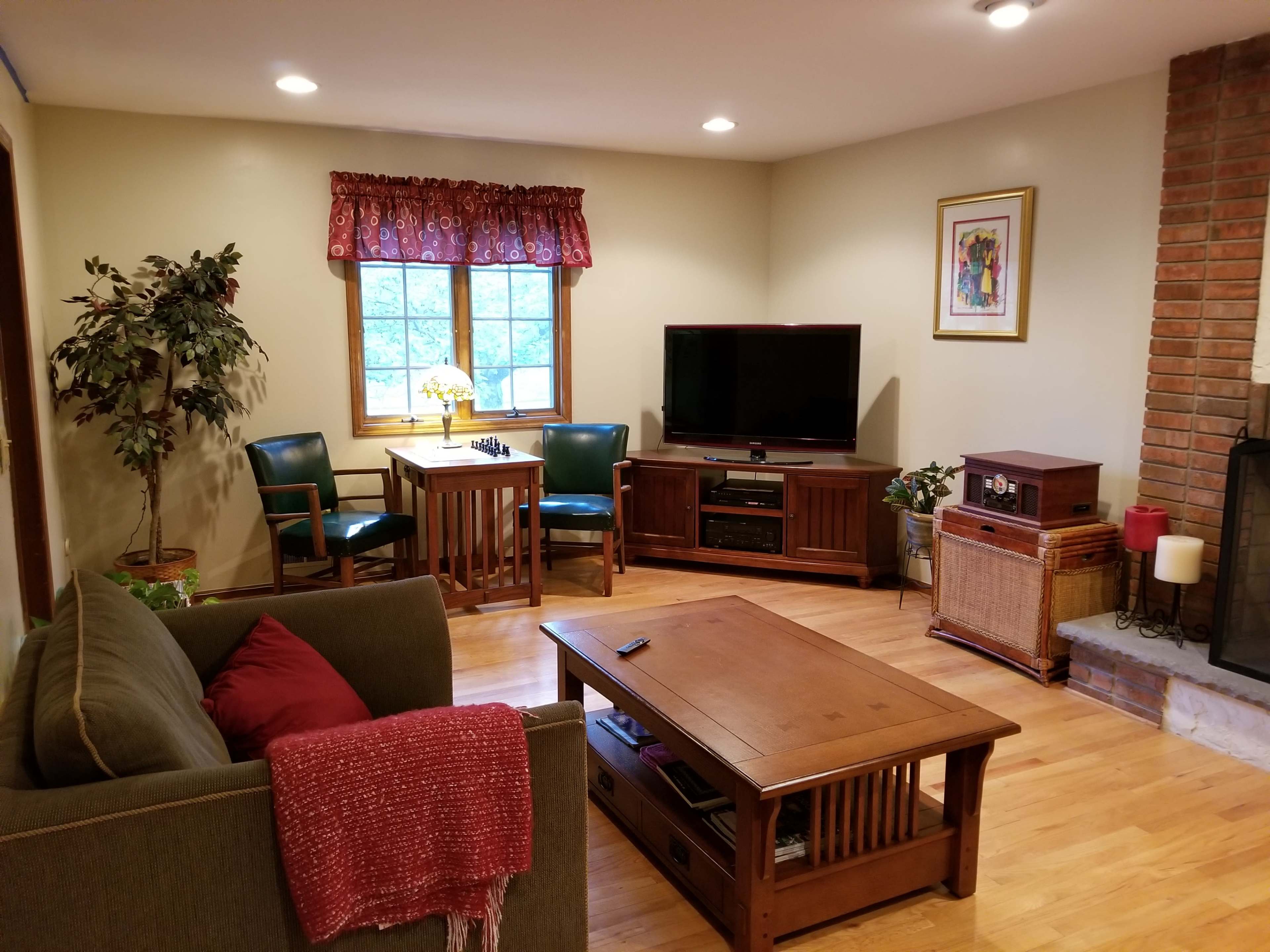 The living room features a green sofa, a wooden coffee table, a television, and a small dining table with chairs near a window.
