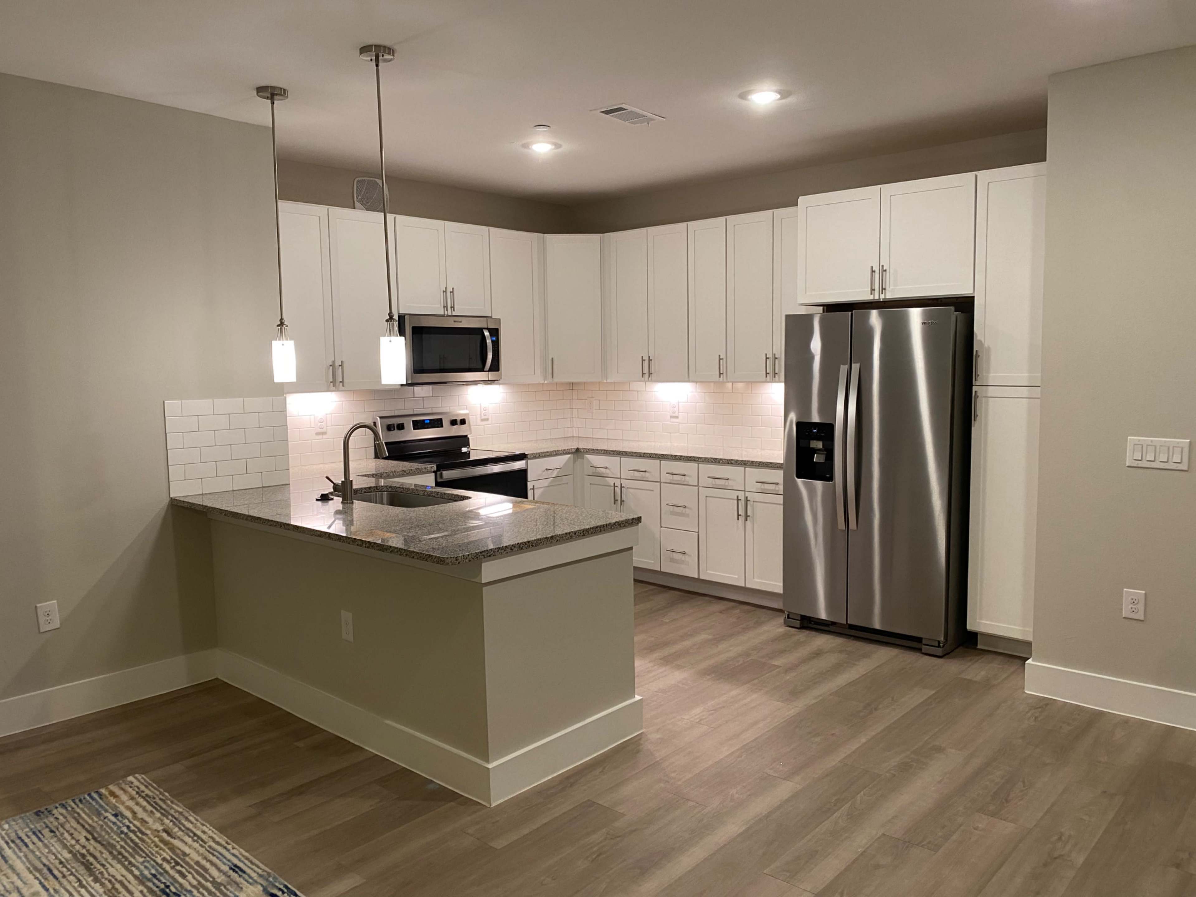 A modern kitchen with white cabinetry, stainless steel appliances, and a granite countertop.