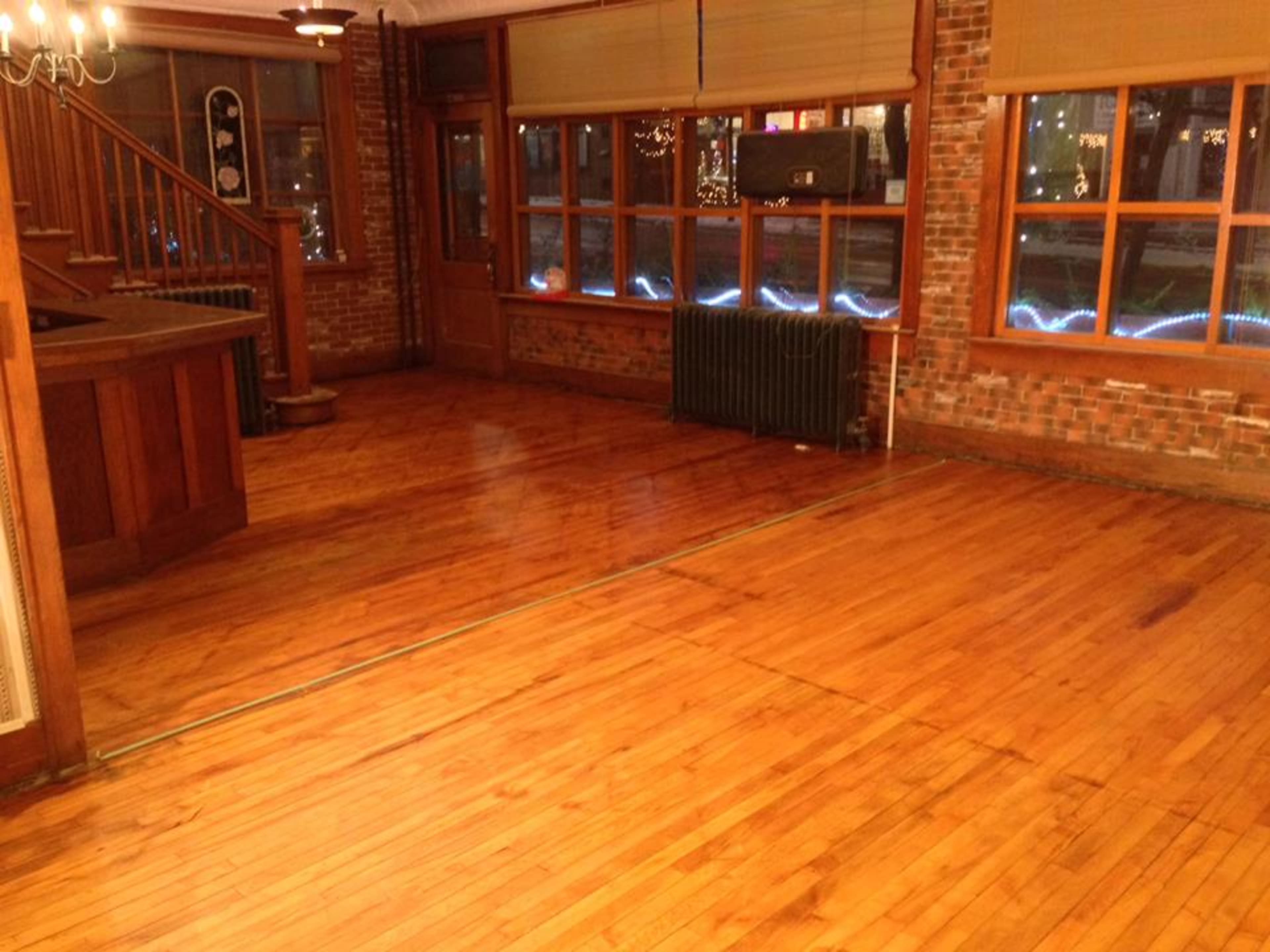 A wooden floor area in a room with exposed brick walls and large windows.