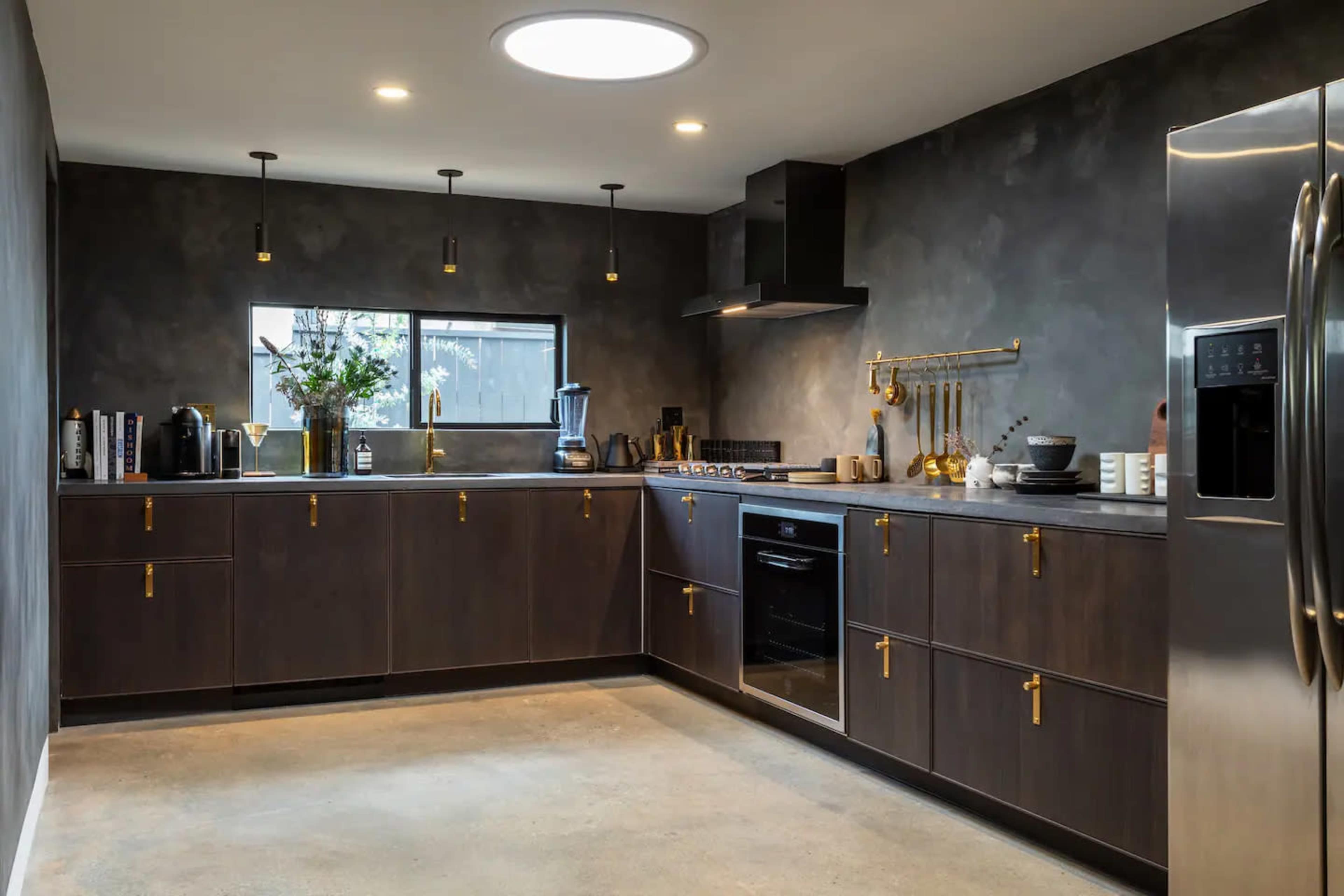 The image showcases a modern kitchen featuring dark wood cabinetry, stainless steel appliances, and an island with a minimalist design.