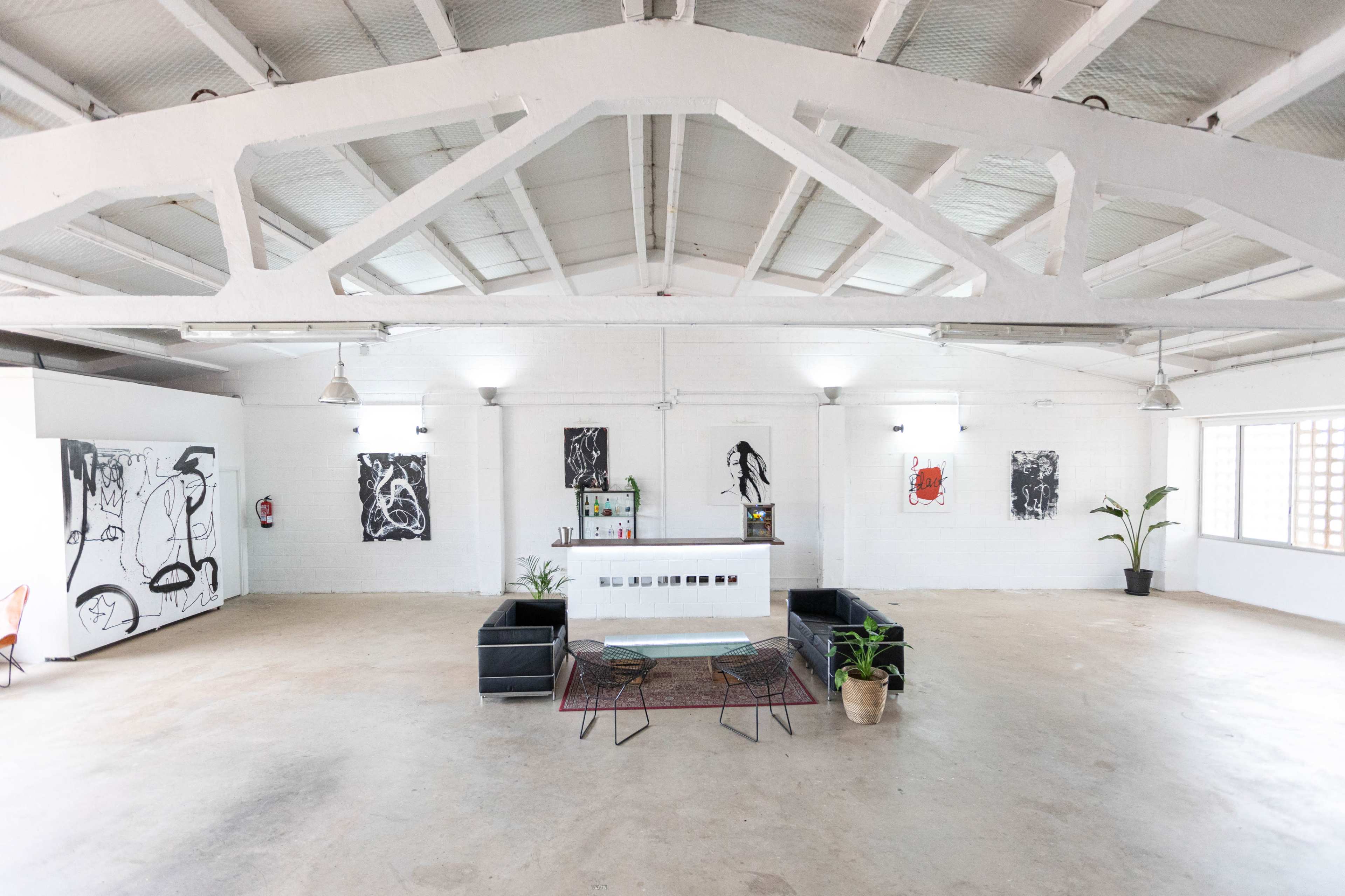 A spacious, minimalist interior of an art gallery with a reception area featuring a seating arrangement and walls adorned with contemporary artwork.