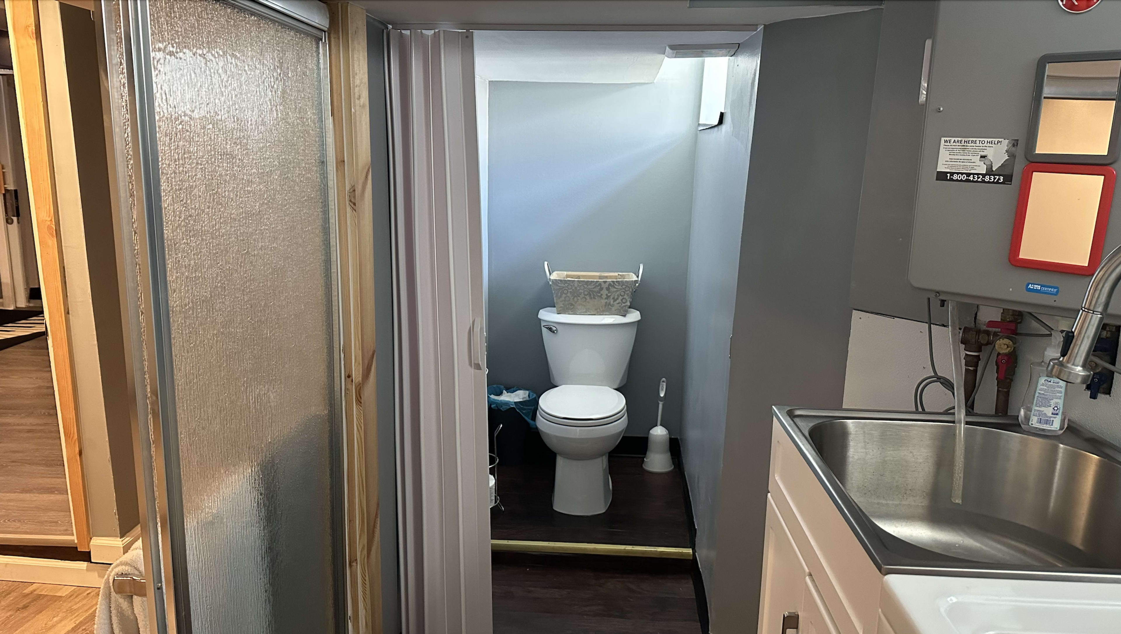 A small bathroom with a toilet, sink, and a shower area partially visible.