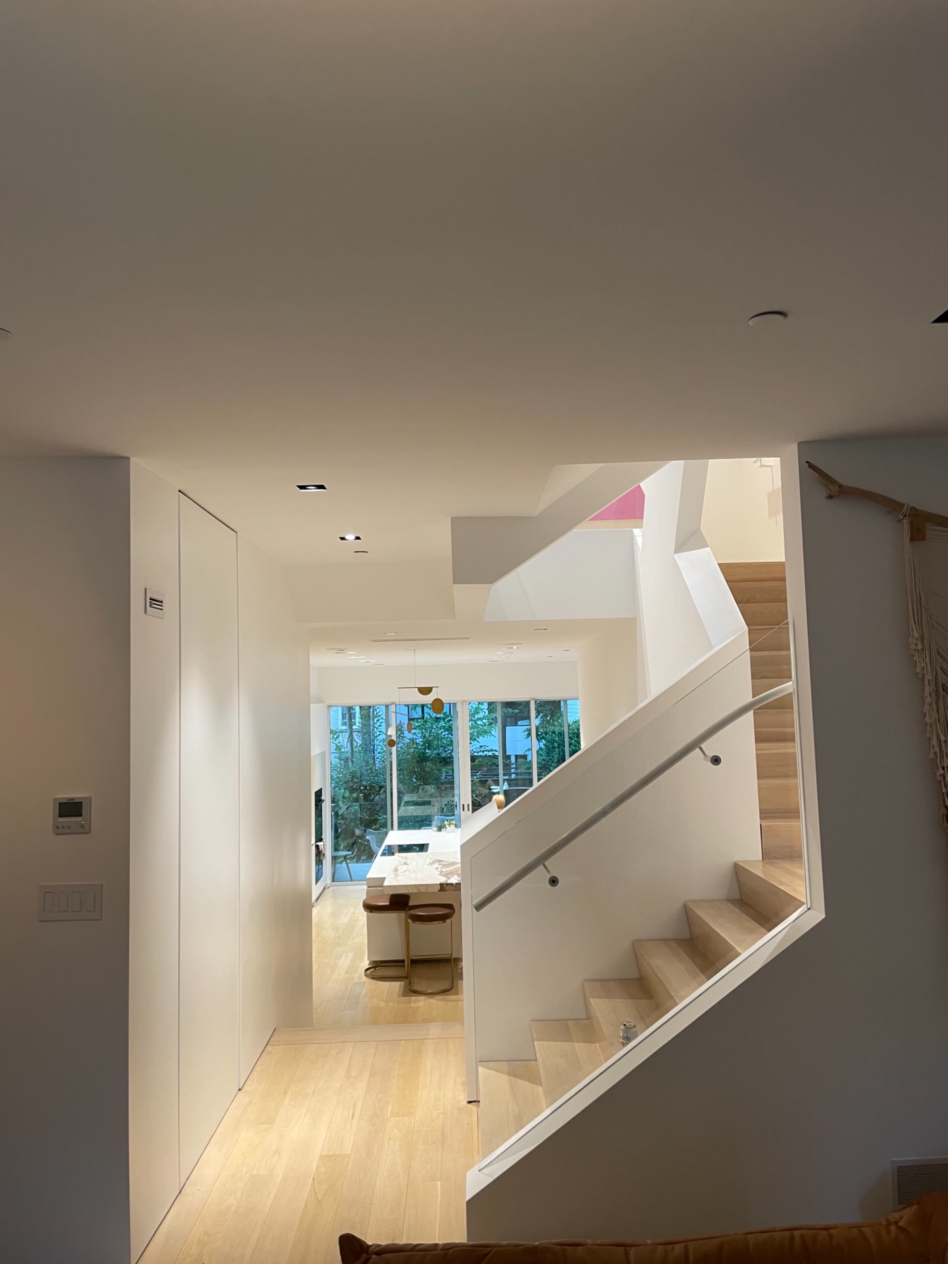 A modern interior space featuring a staircase leading to an upper level, with a dining area visible in the background.