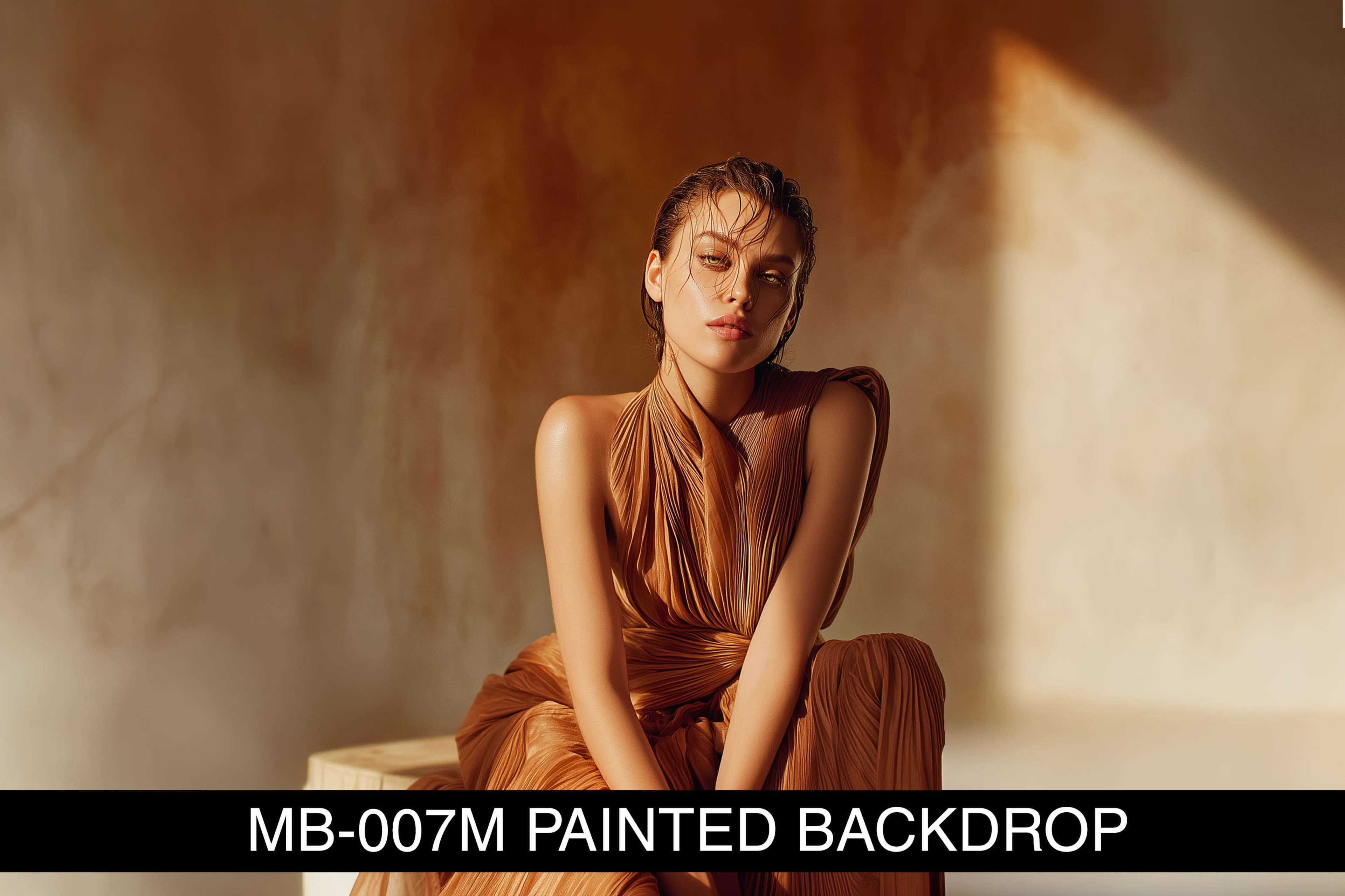 A woman poses in a flowing, textured brown dress against a softly lit, painted backdrop.