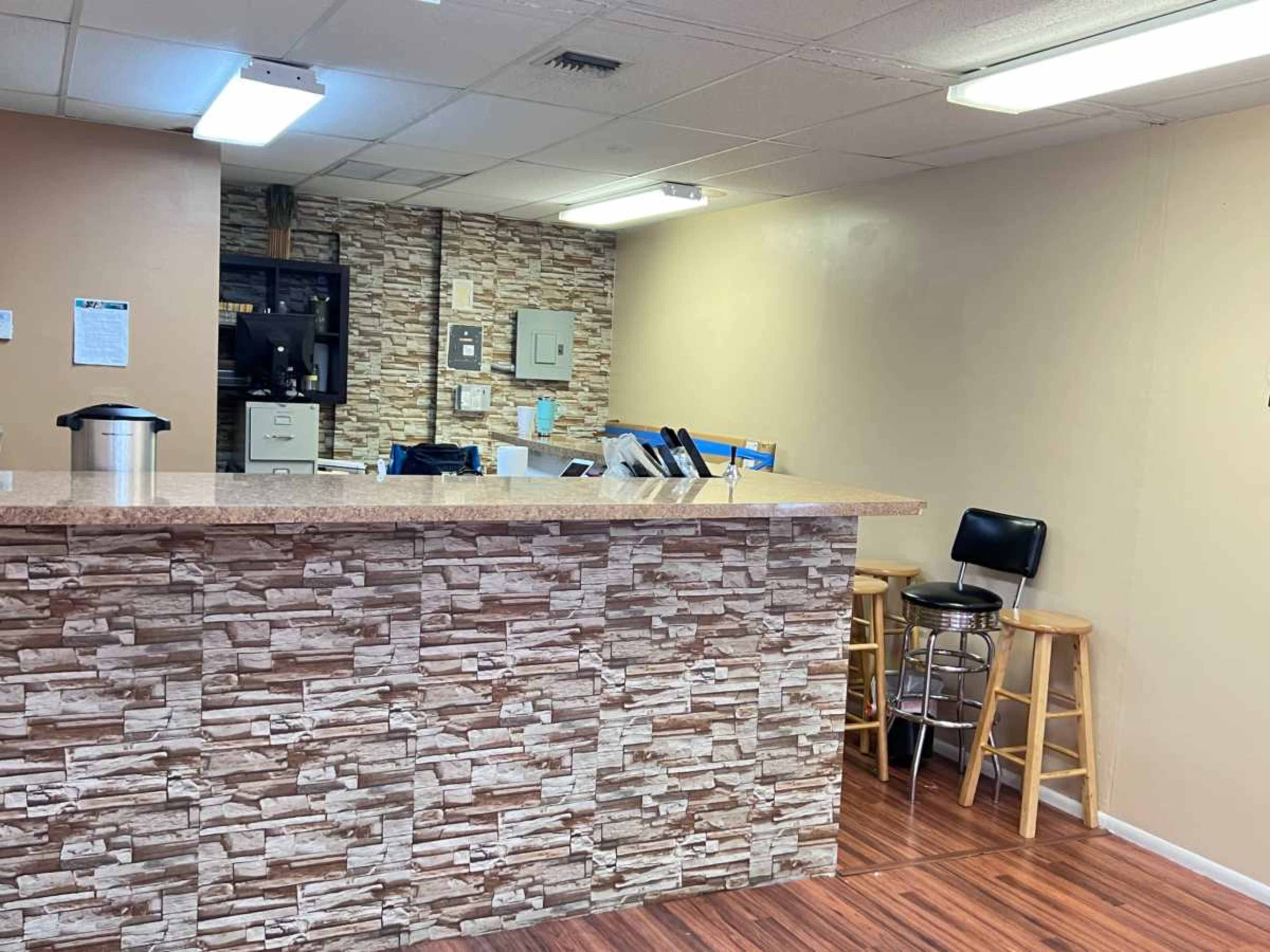 A reception area with a stone-patterned front desk, two wooden stools, and a wall-mounted cabinet in the background.