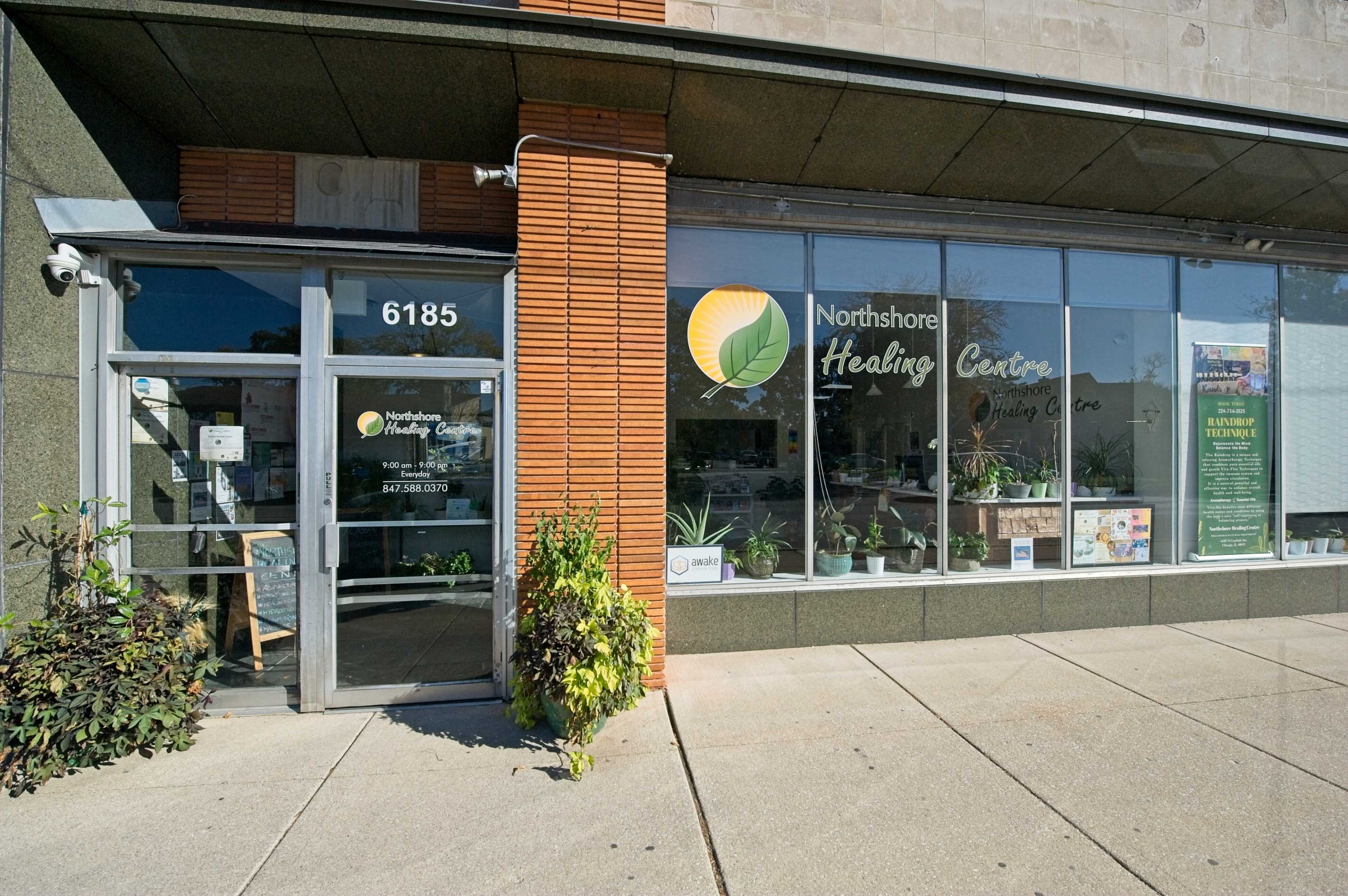 The image shows the storefront of Northshore Healing Centre with large windows displaying plants and health-related information.
