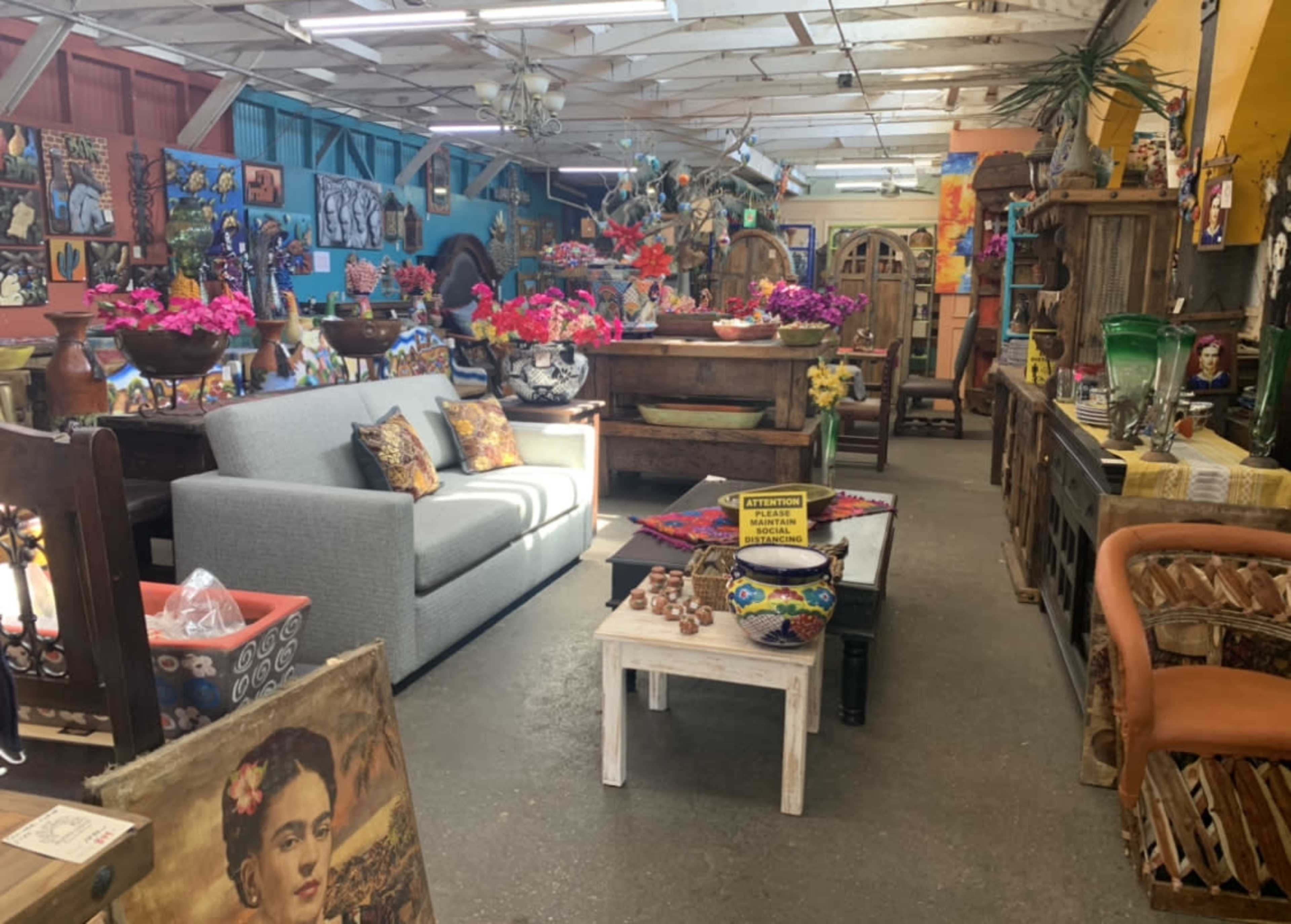 The image shows a colorful antique shop filled with various decorative items, furniture, and vibrant floral arrangements.