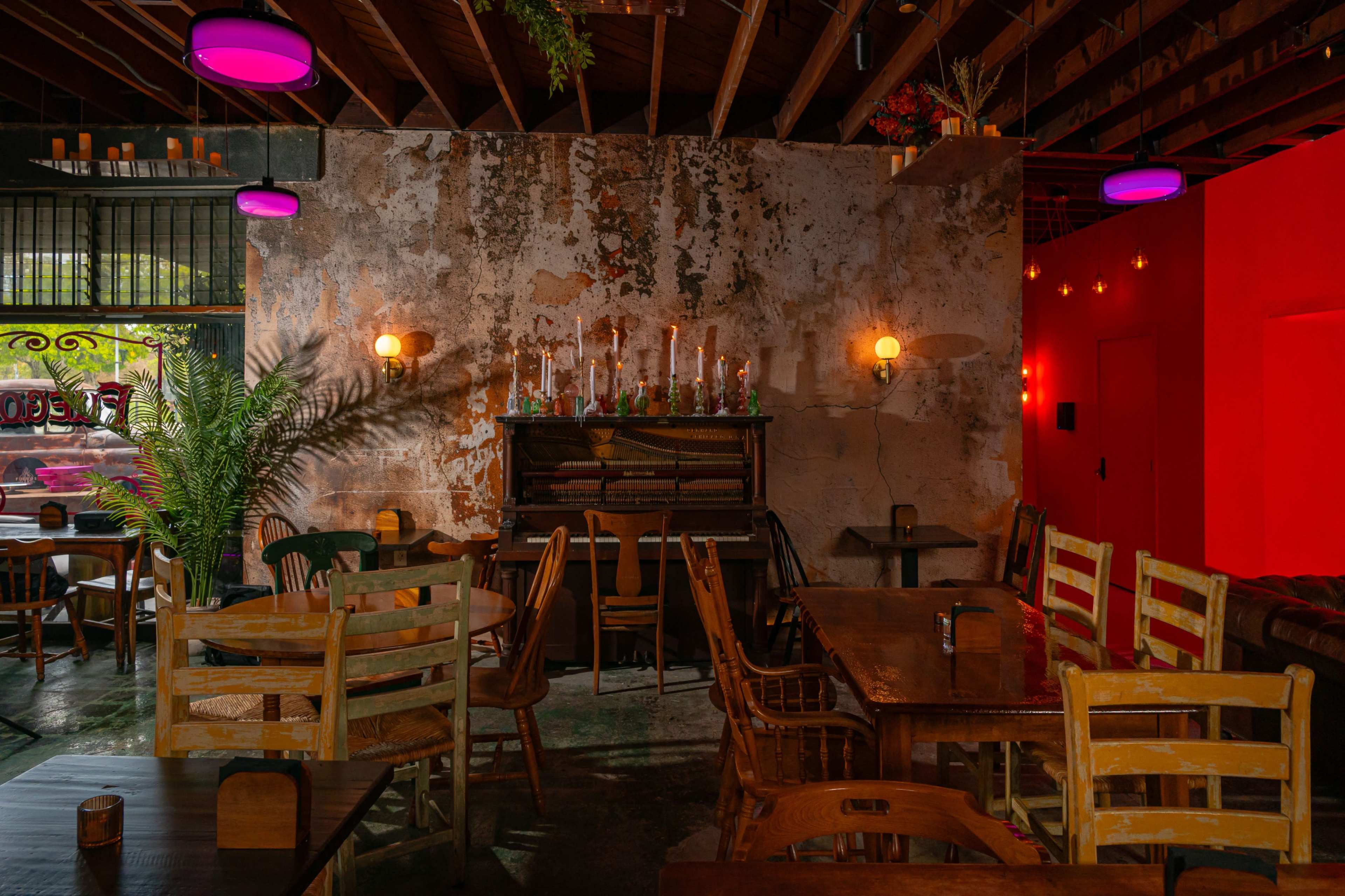 The image shows a rustic restaurant interior with exposed brick walls, wooden furniture, and a decorative piano against the wall, illuminated by soft lighting.