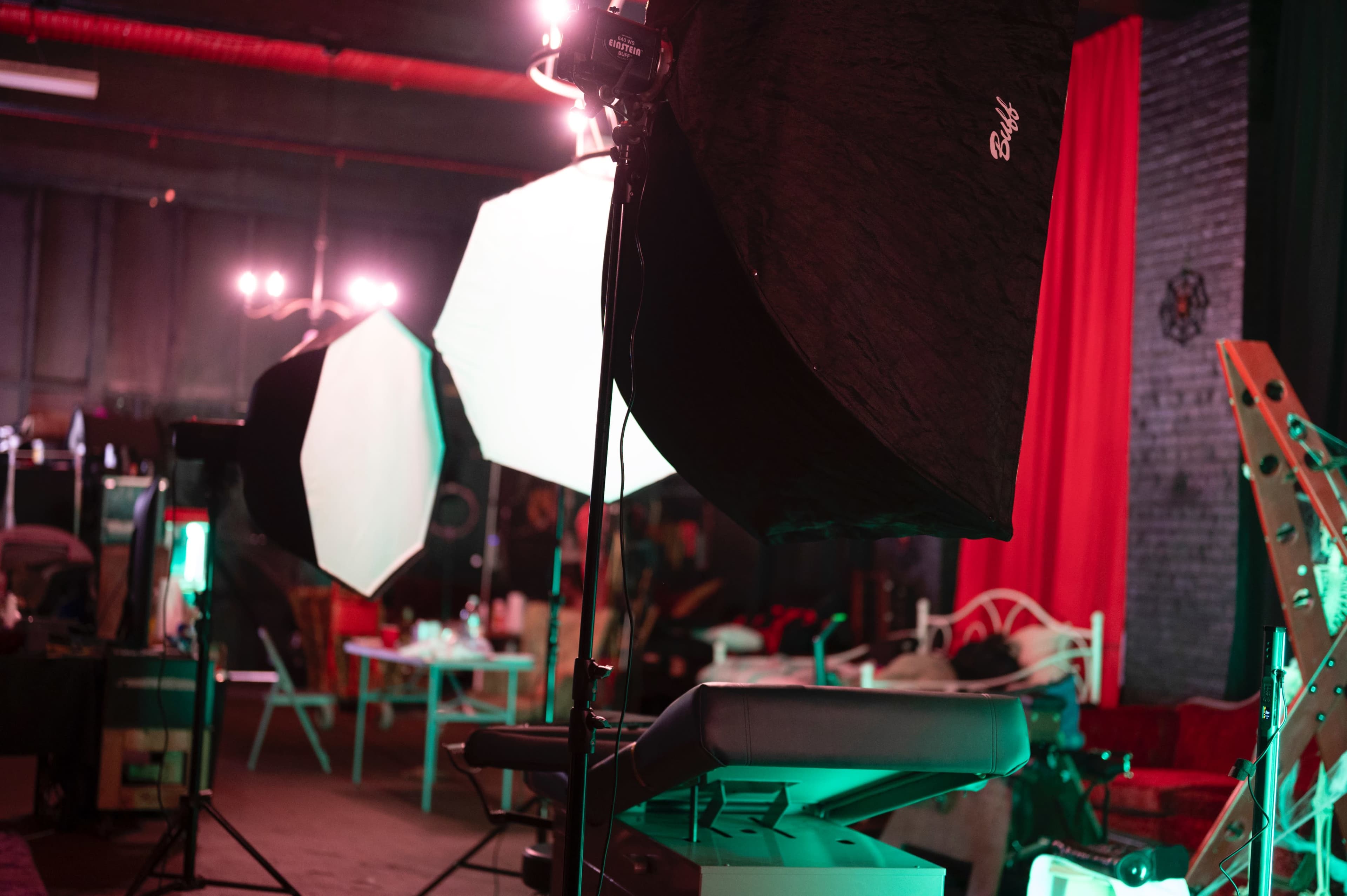 The image shows a photography studio equipped with softbox lights, a keyboard on a stand, and various props in a dimly lit environment.