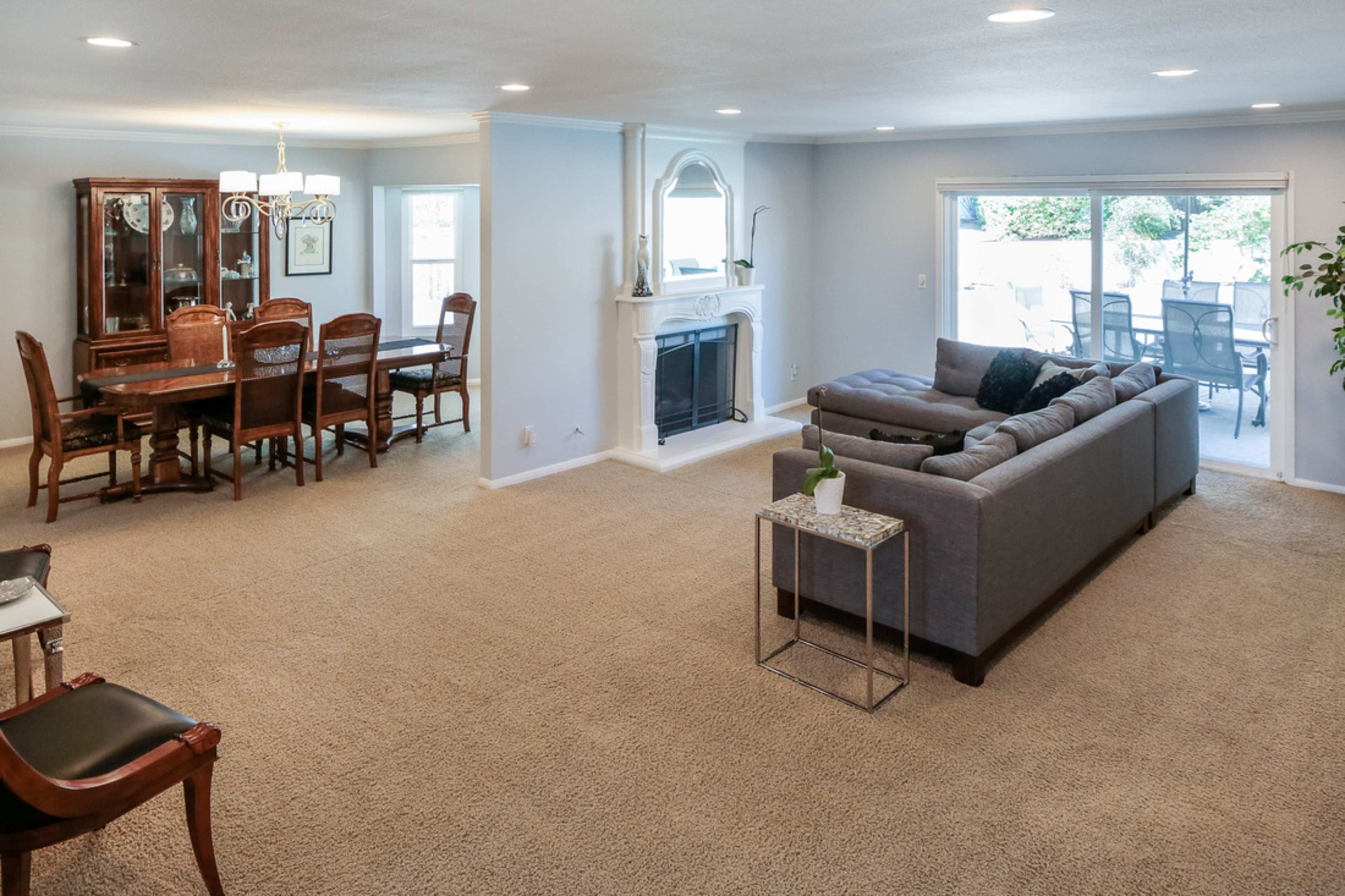 A spacious living room with a gray sofa and a dining area featuring a wooden dining set and a fireplace.