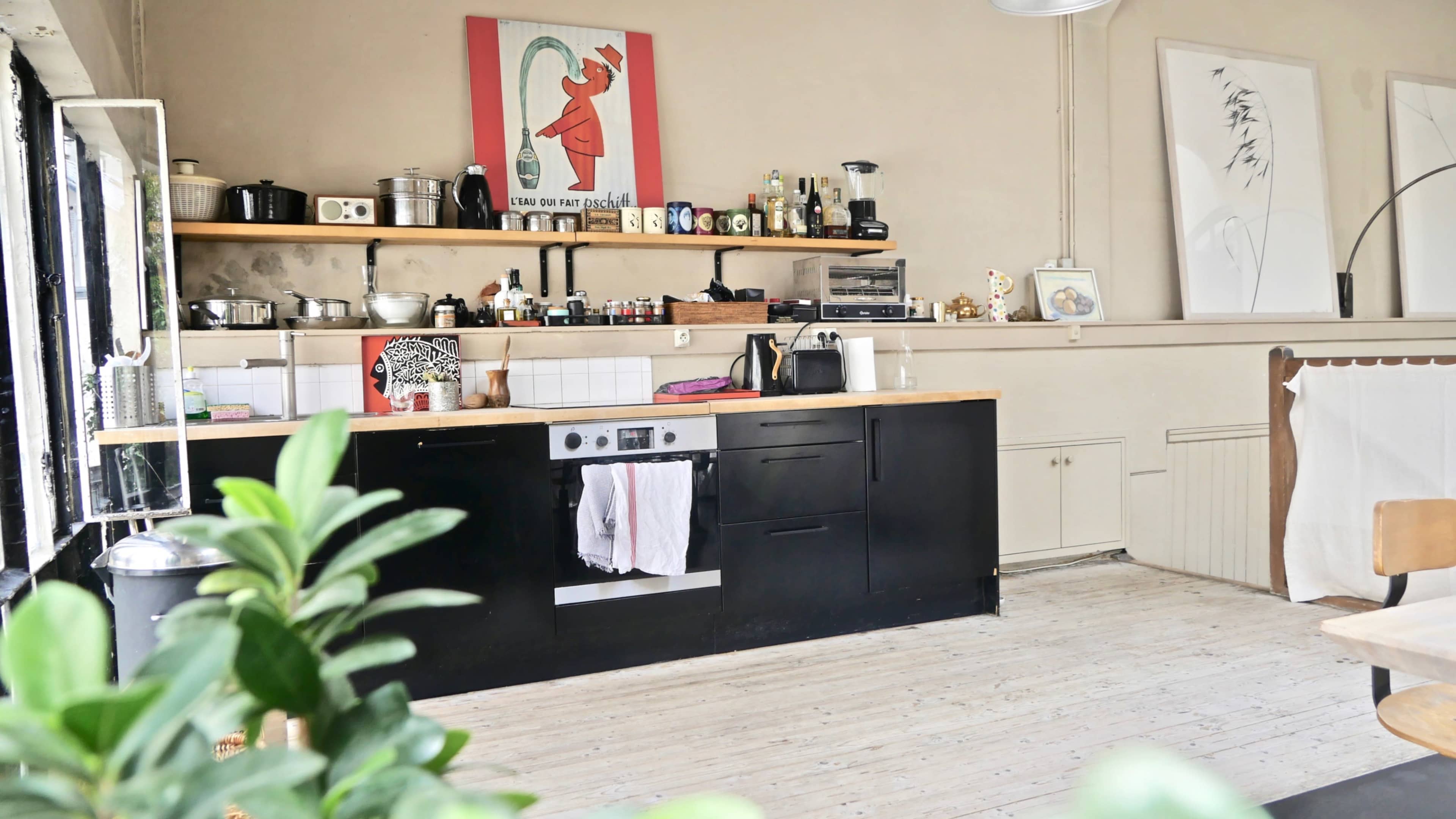 A modern kitchen features a black island with a wooden countertop, equipped with various appliances and decor on the walls.