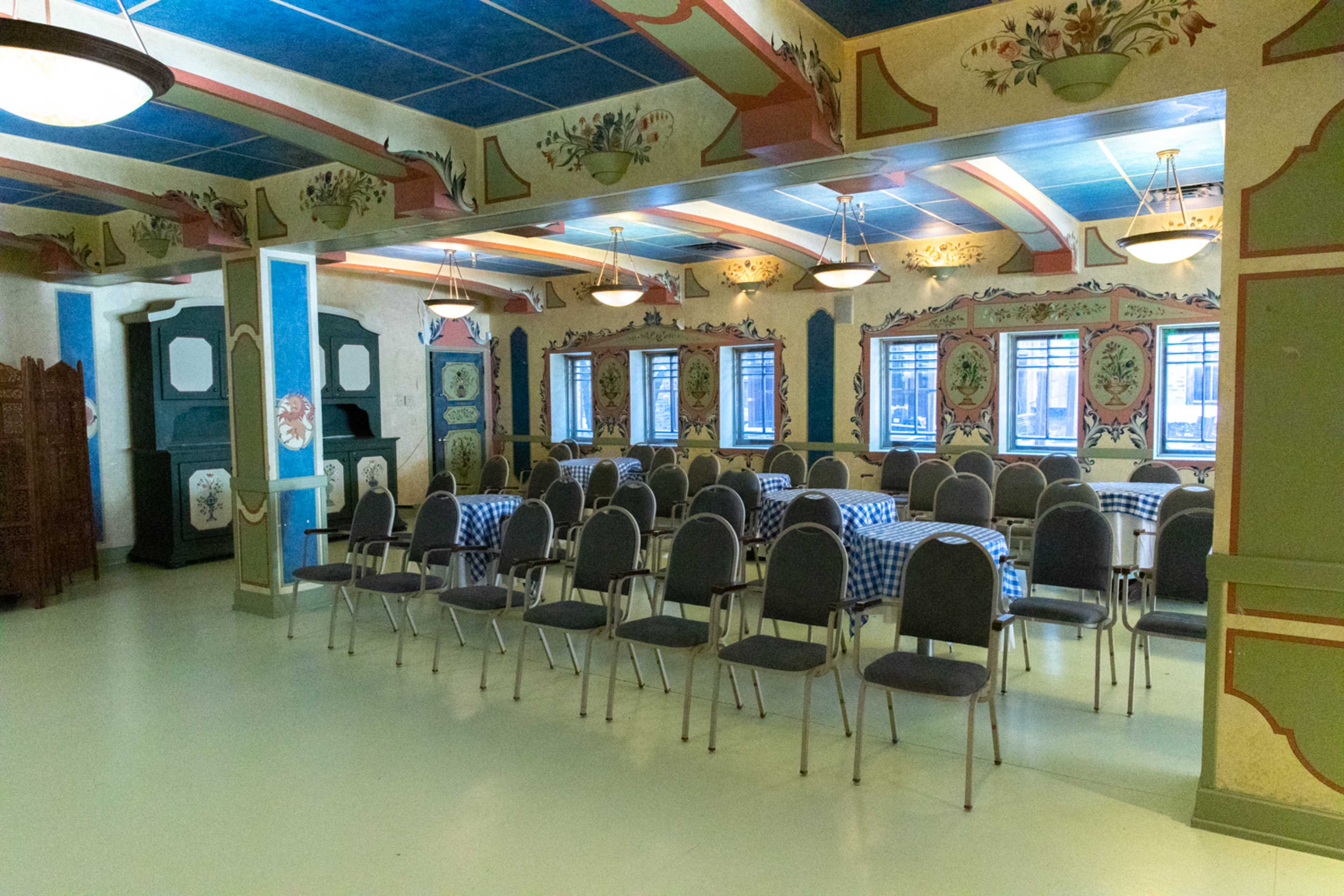The room features rows of chairs arranged facing a decorated wall with floral patterns and a blue ceiling.