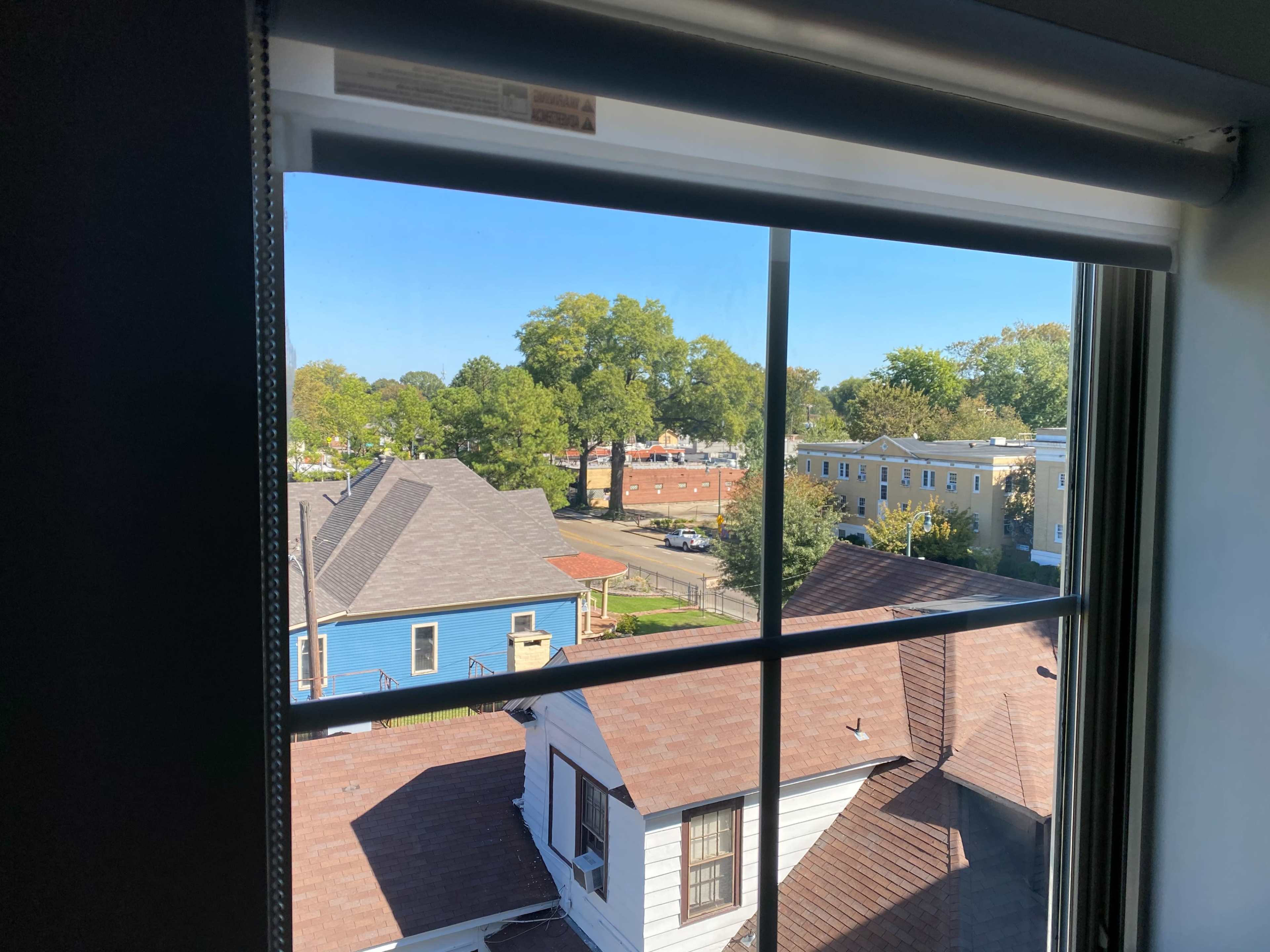A view from a window overlooking rooftops of houses and a clear blue sky.