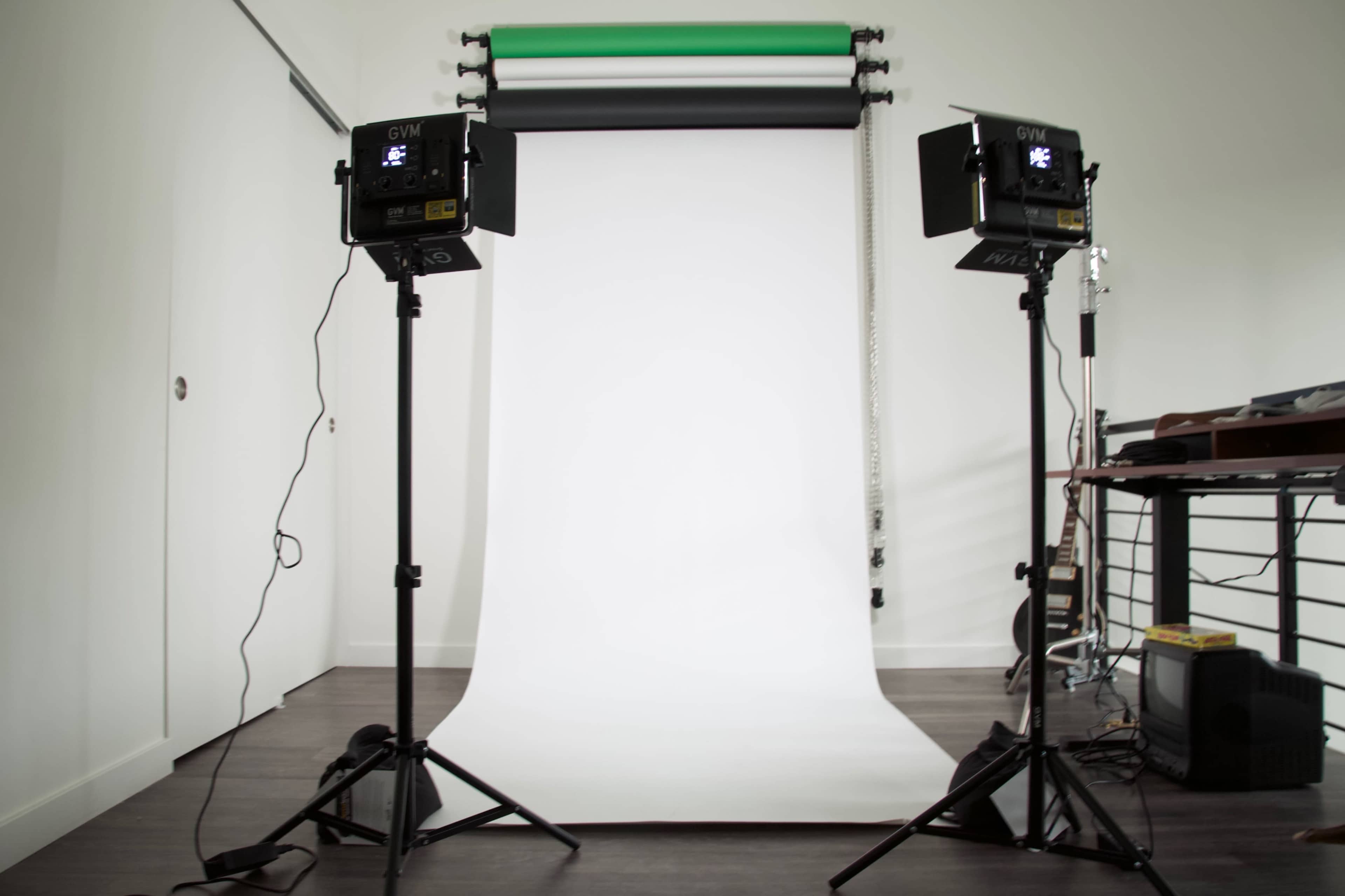A photography studio setup with two lights on stands facing a white backdrop.