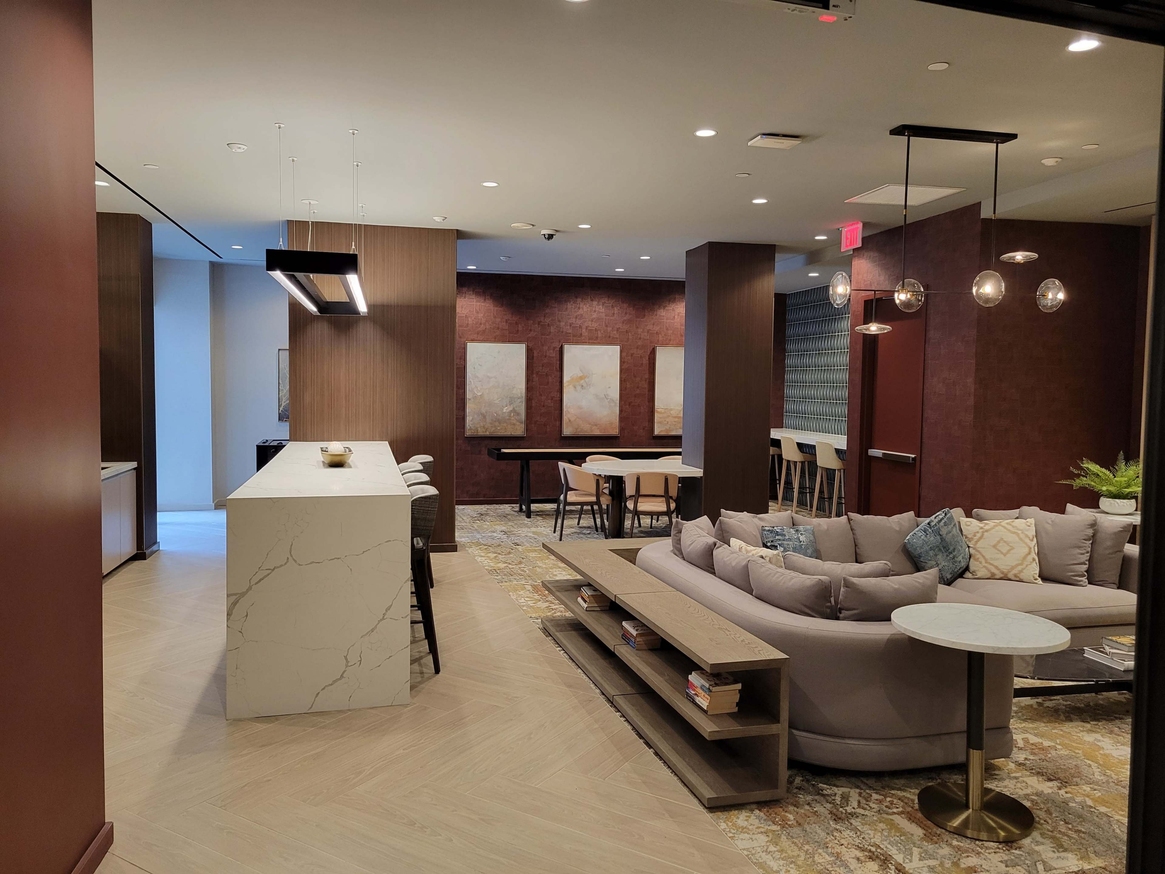 A modern, open-concept lounge area with a kitchen island, seating spaces, and decorative artwork on the walls.