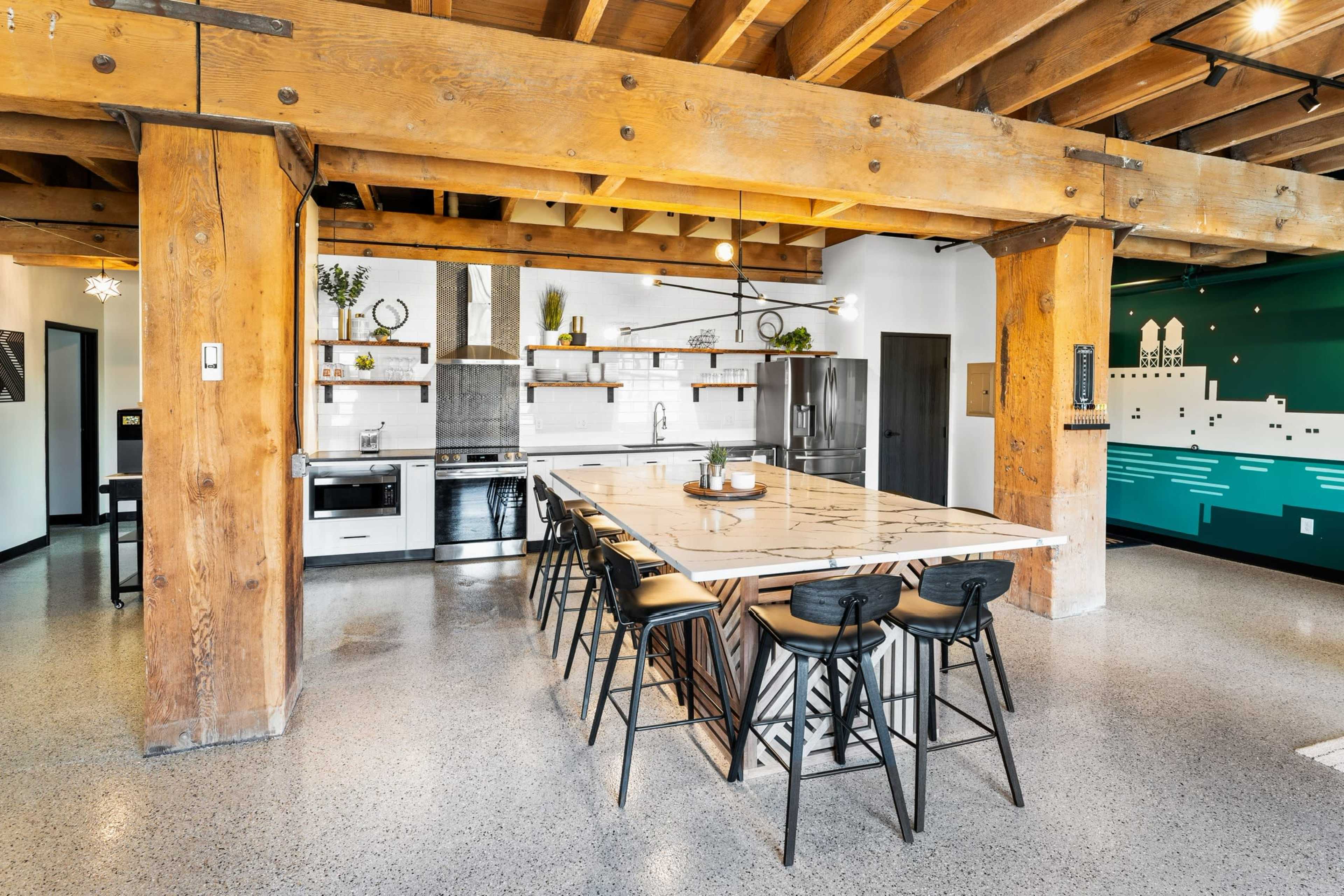 A modern kitchen with a large island, wooden beams, and stainless steel appliances.