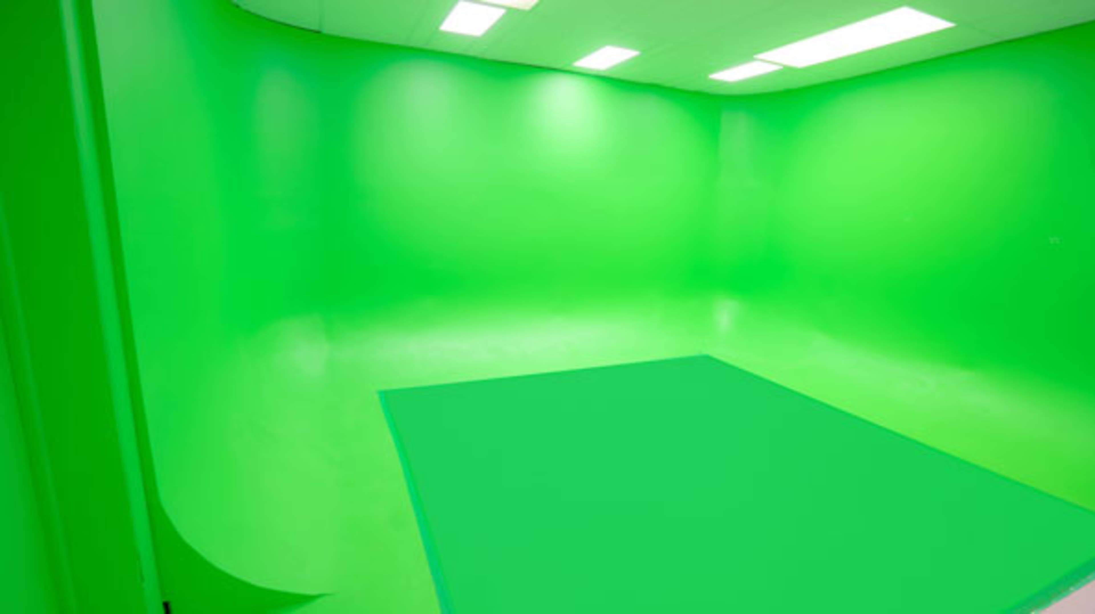 The image shows a green studio space with seamless green walls and flooring.