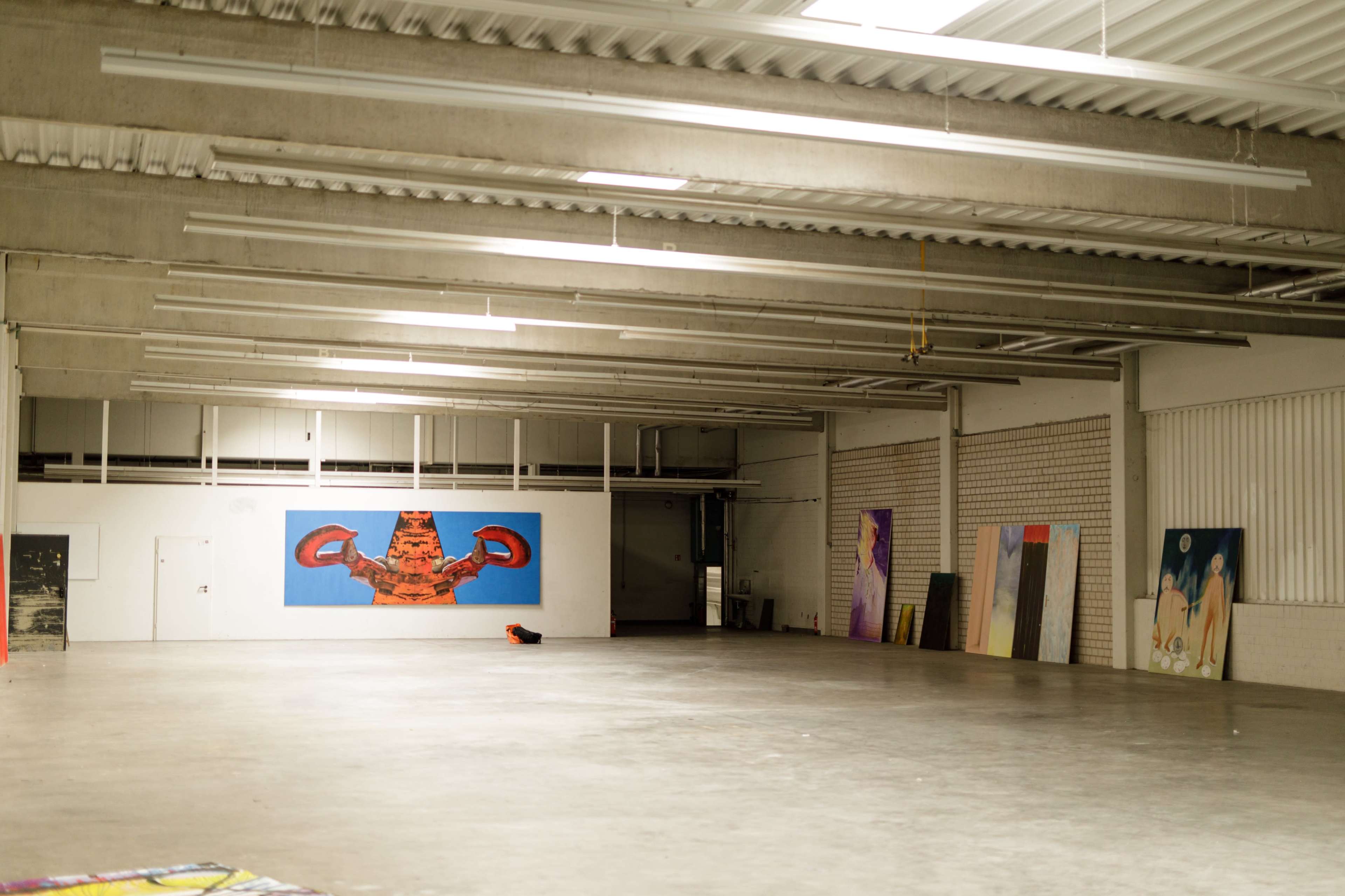 The image shows a spacious, empty art gallery with several large paintings displayed on the walls.