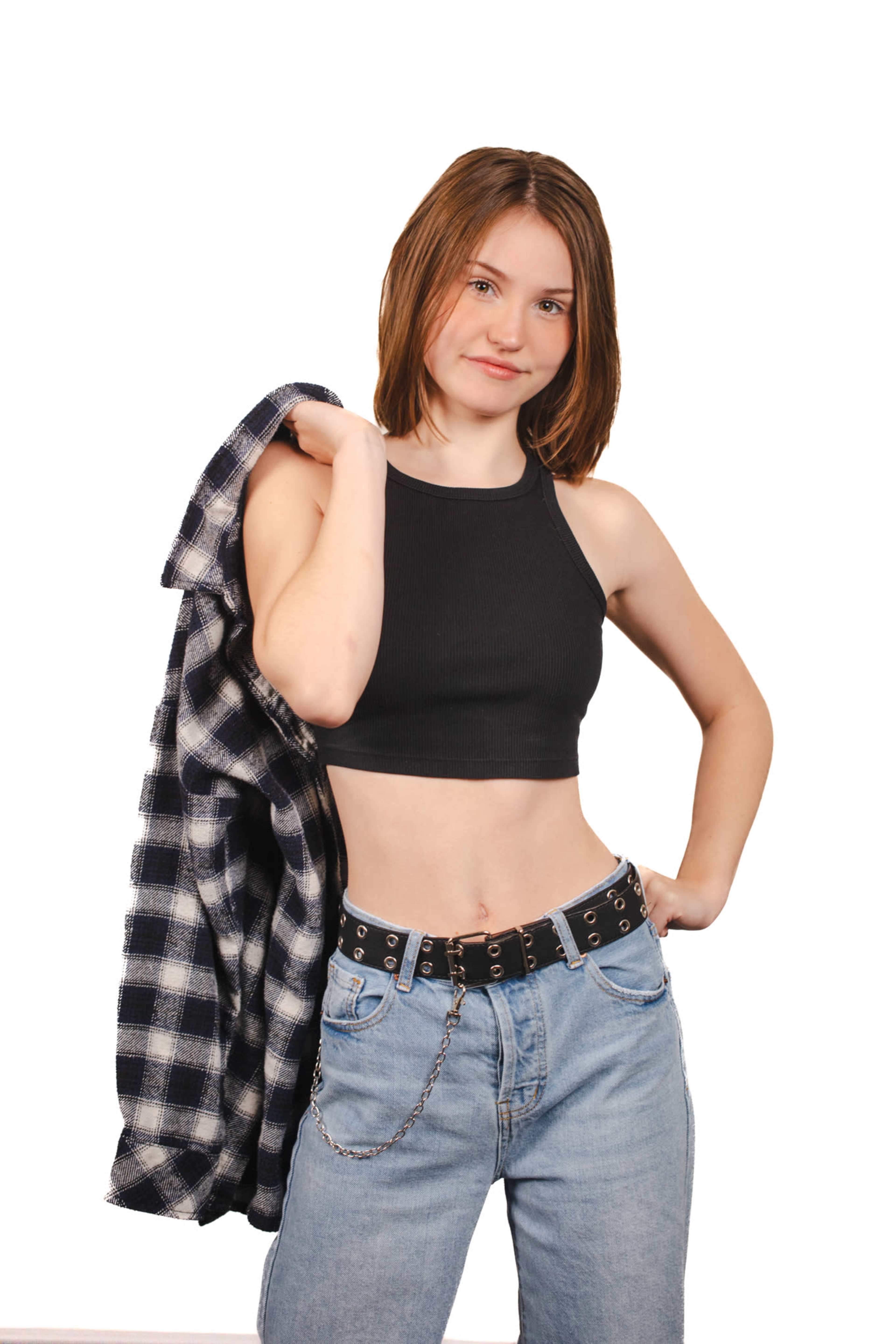 A young woman in a black crop top and blue jeans holds a flannel shirt over her shoulder.