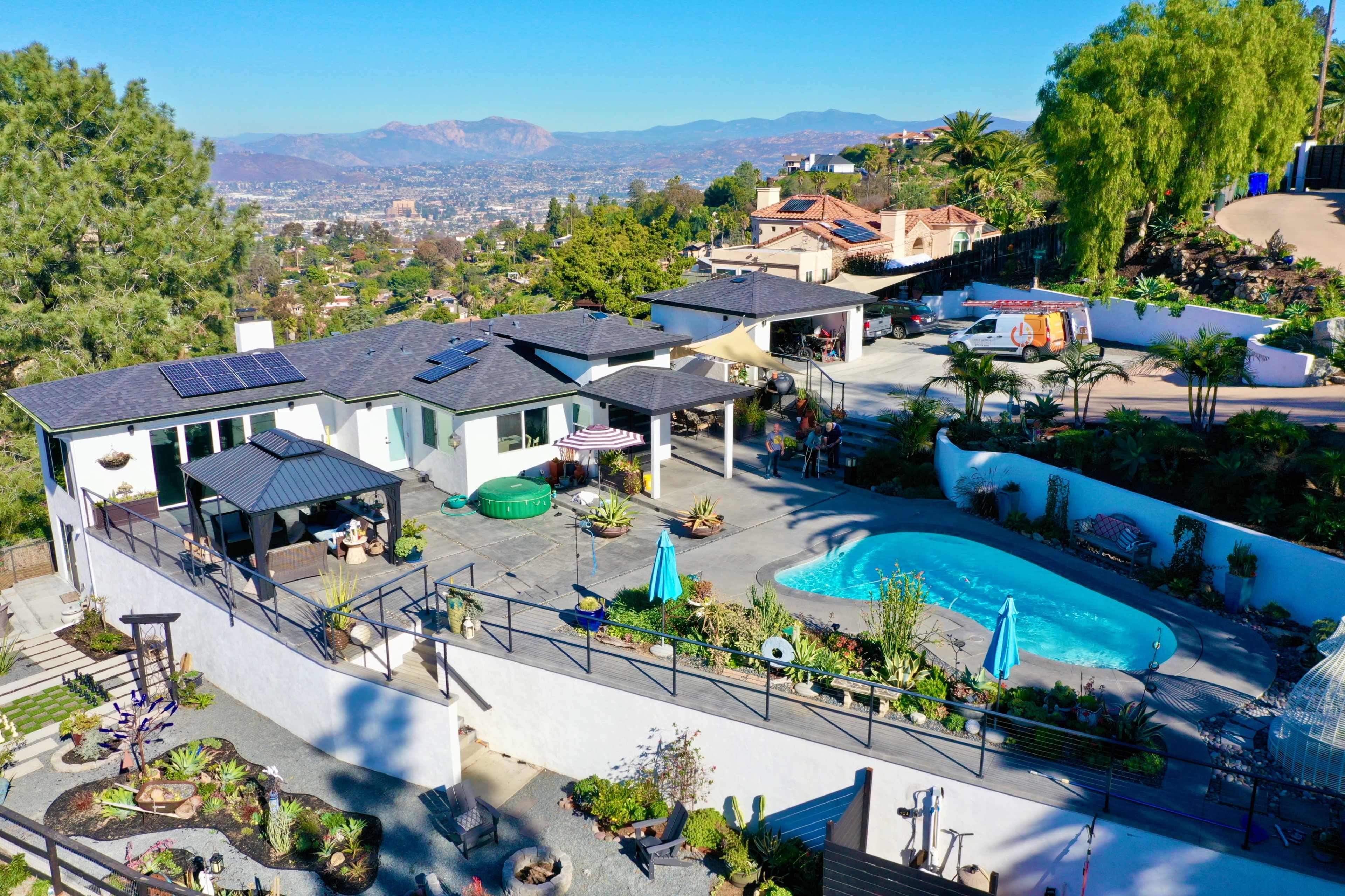 A residential property with a swimming pool, patio area, and scenic views of distant mountains and a cityscape.