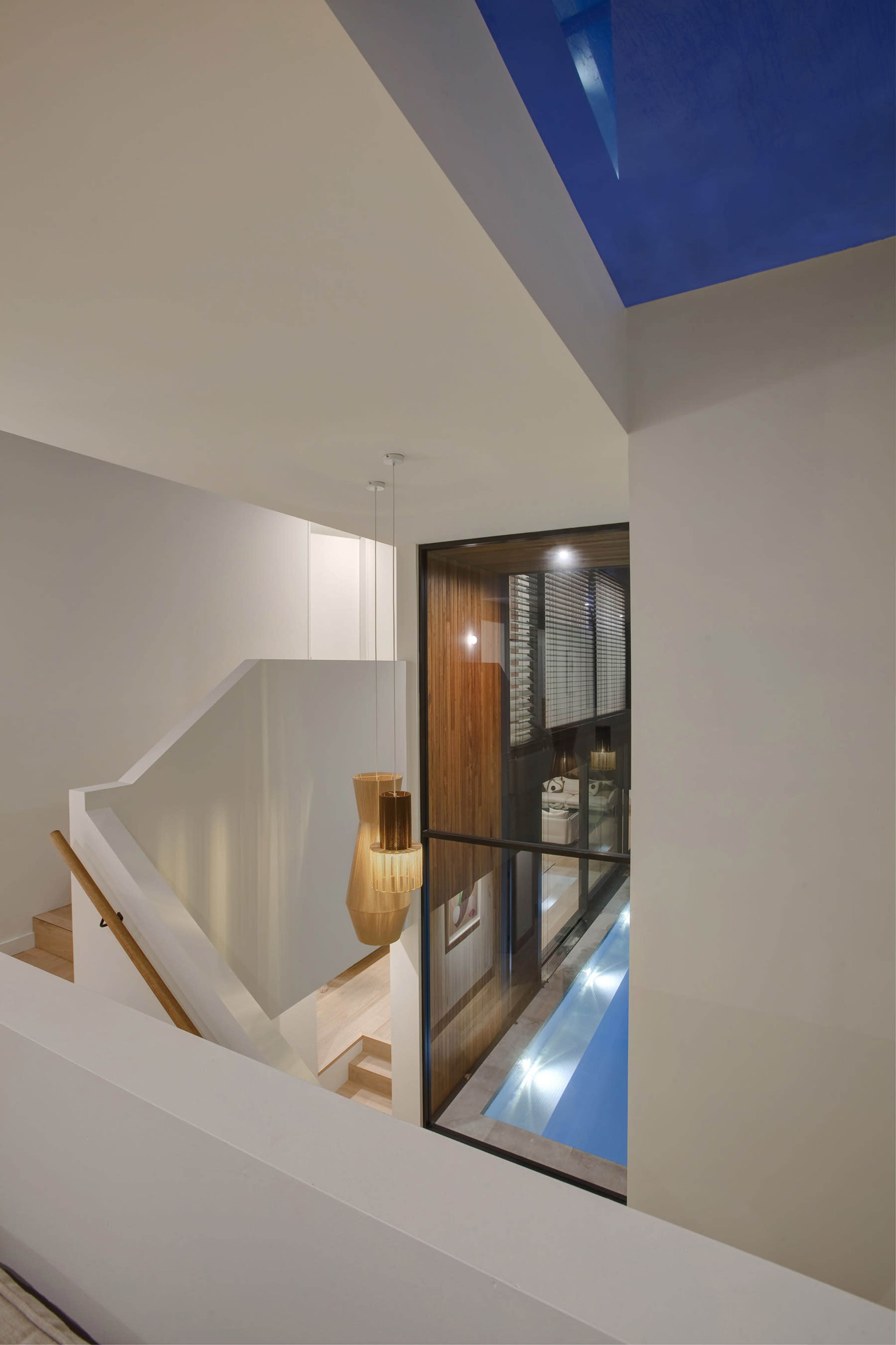 A modern interior view of a home featuring a staircase, large windows, and a pool below.