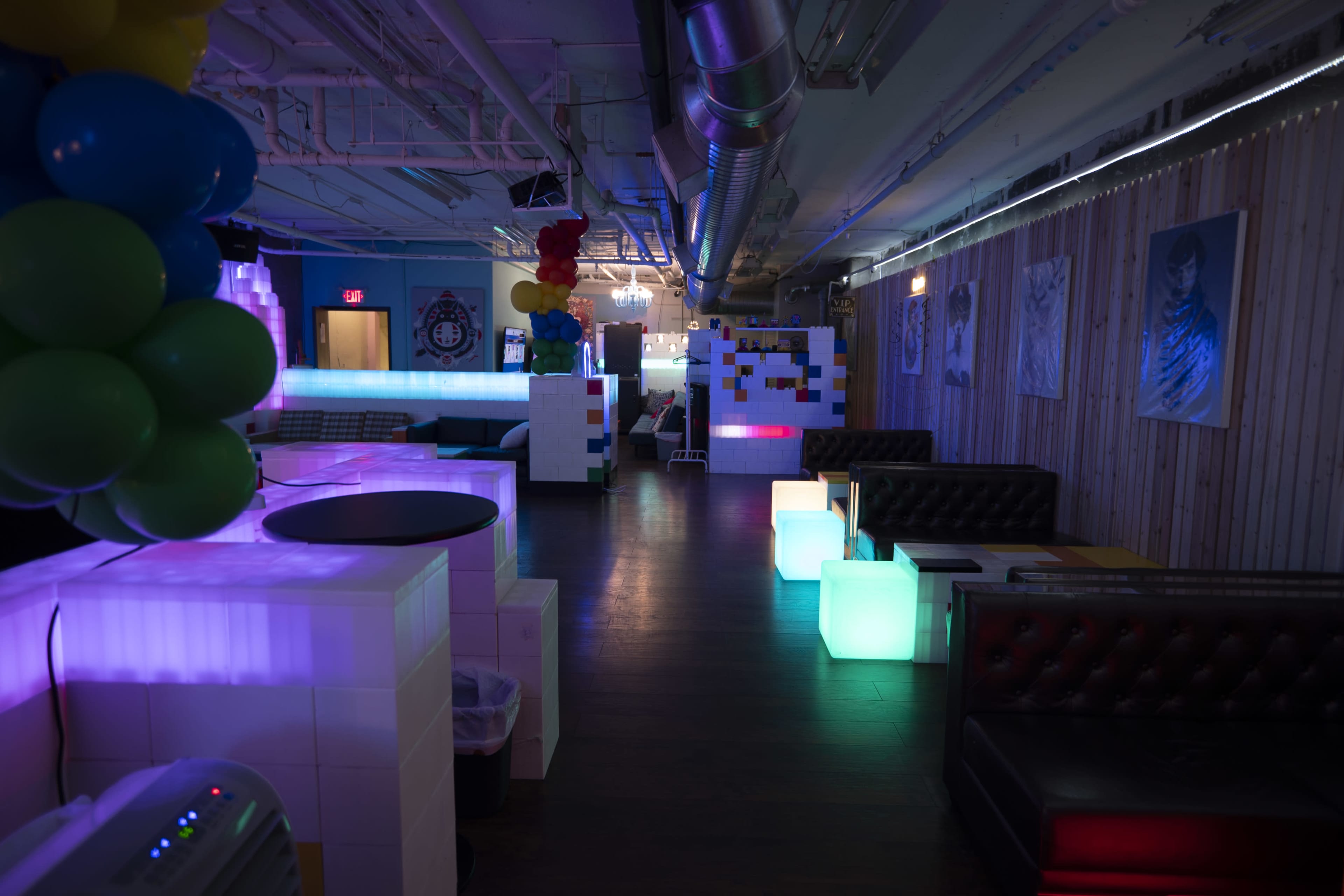 A brightly lit lounge area with illuminated furniture and decorative elements, featuring a mix of sofas and sectioned spaces.