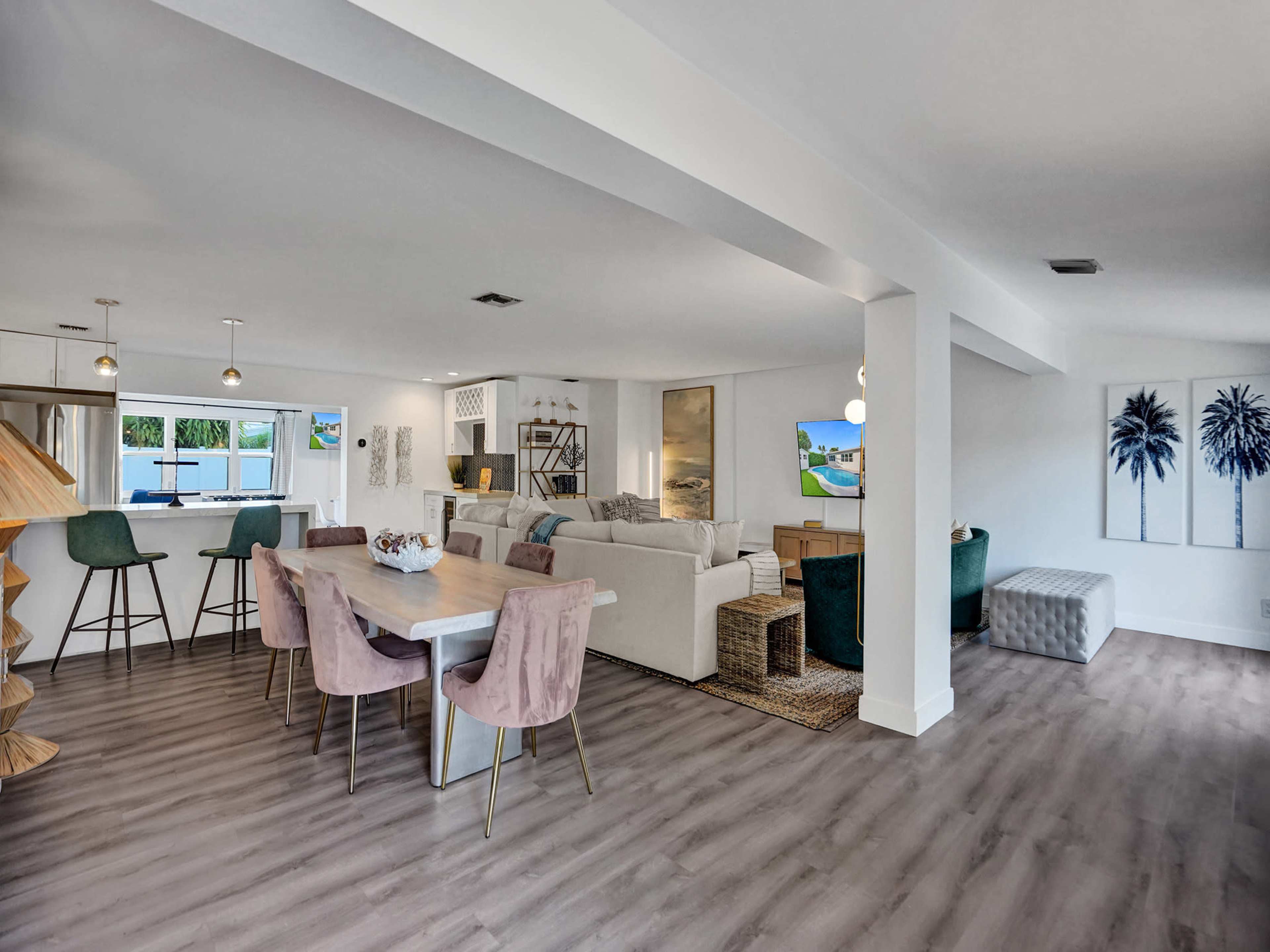 A modern open-concept living space with a dining area featuring a table and chairs, a cozy lounge area with a sofa, and large windows allowing natural light.