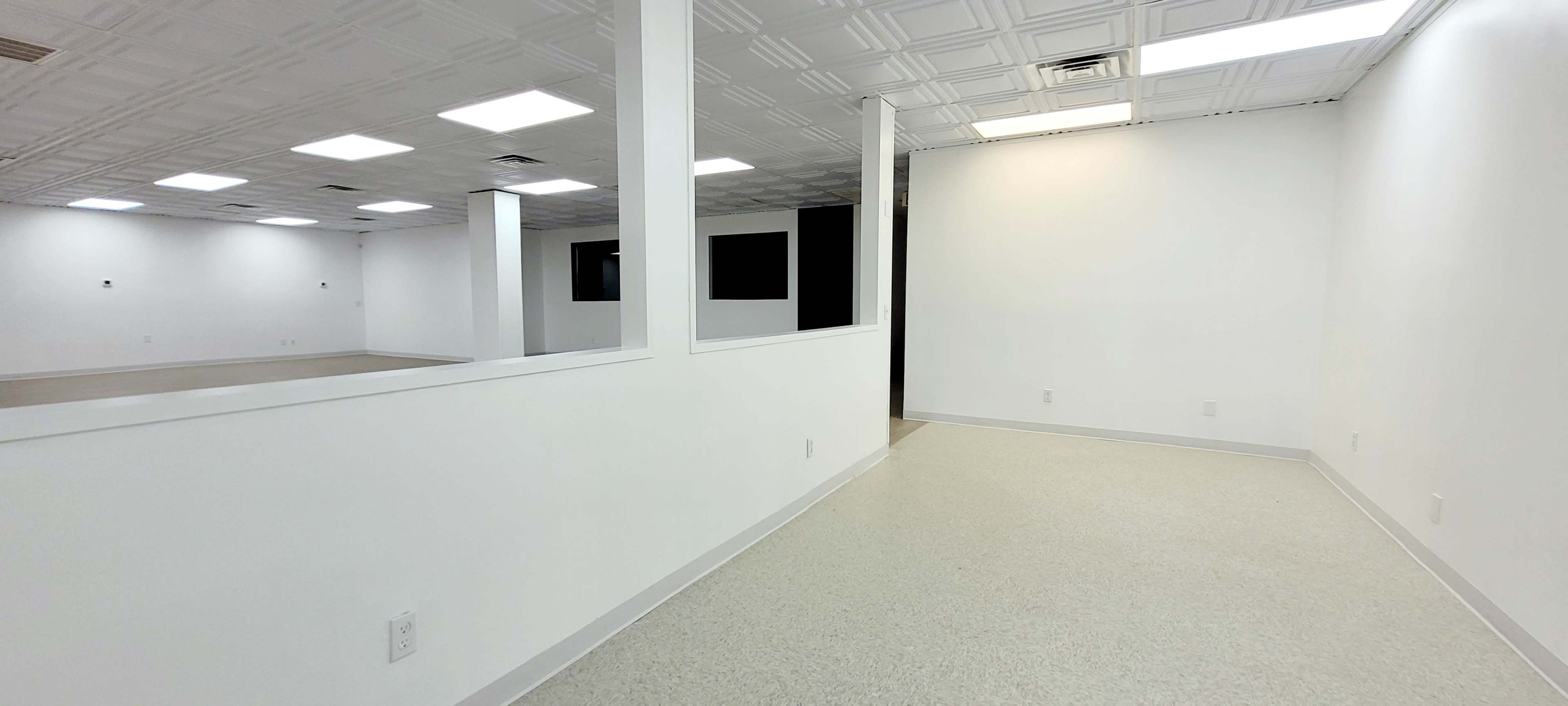 A spacious, well-lit room with white walls, a tiled ceiling, and a smooth floor.