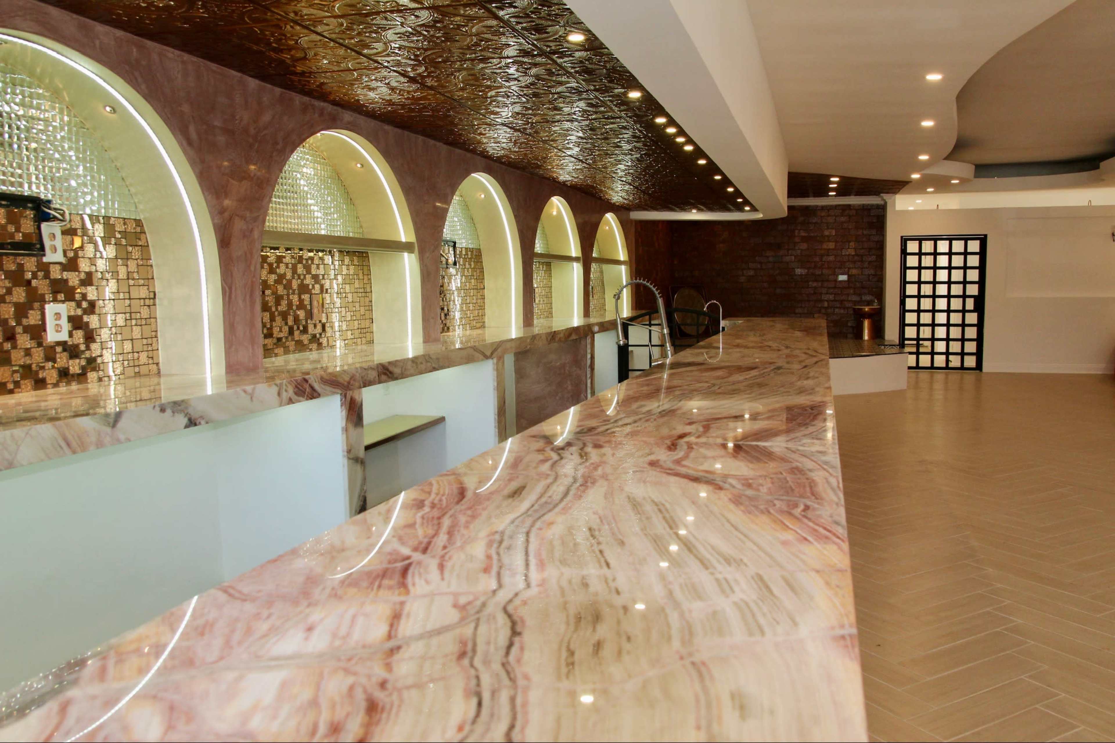 A modern interior features a long marble countertop with arched openings and decorative wall tiles.
